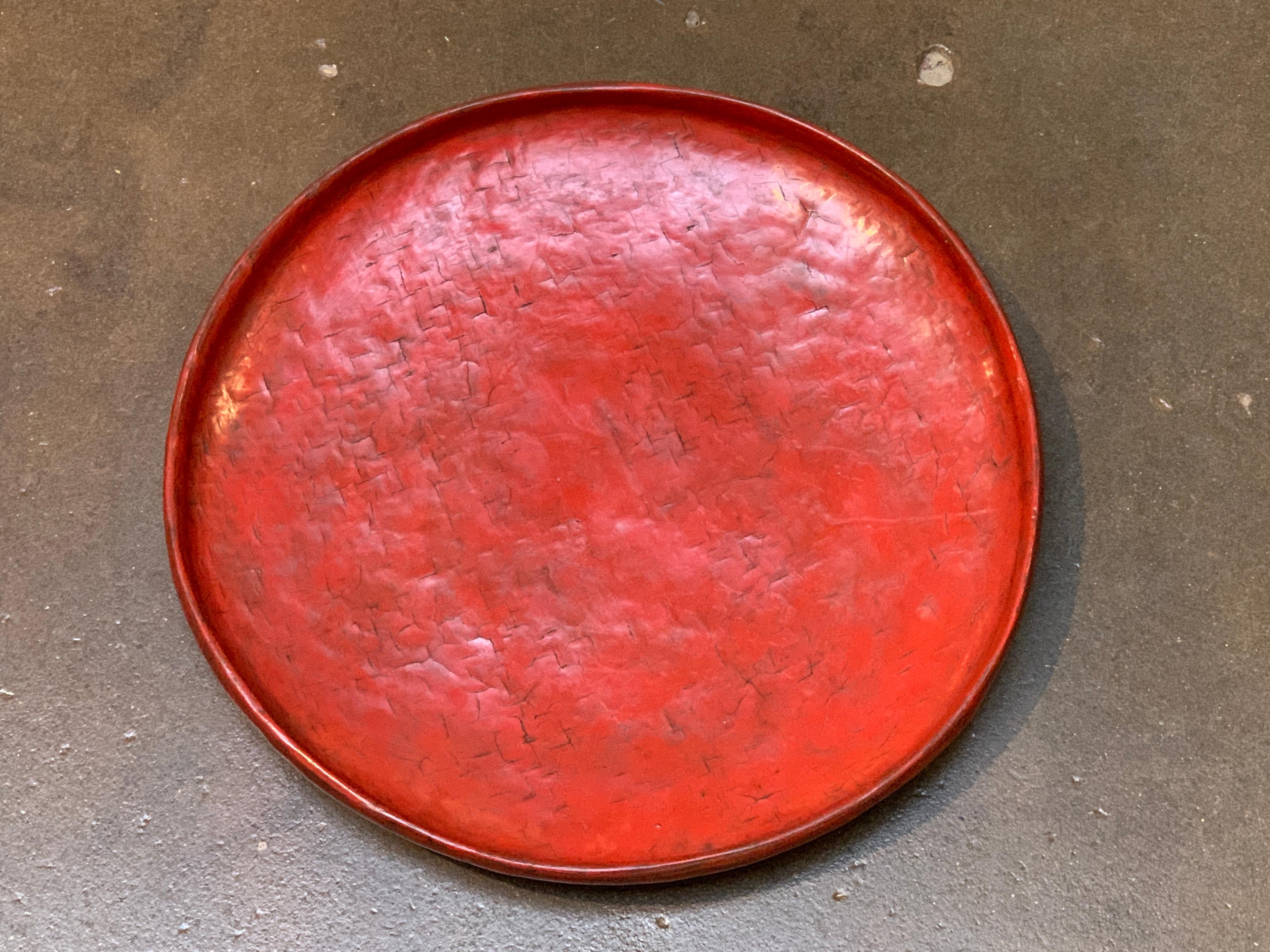 A striking large woven bamboo and red lacquer round tray, Burma (Myanmar) late 19th century. 

The Burmese red lacquered circular tray of slightly irregular shape with a rounded bottom, most likely used as an offering tray to serve monks. Crafted