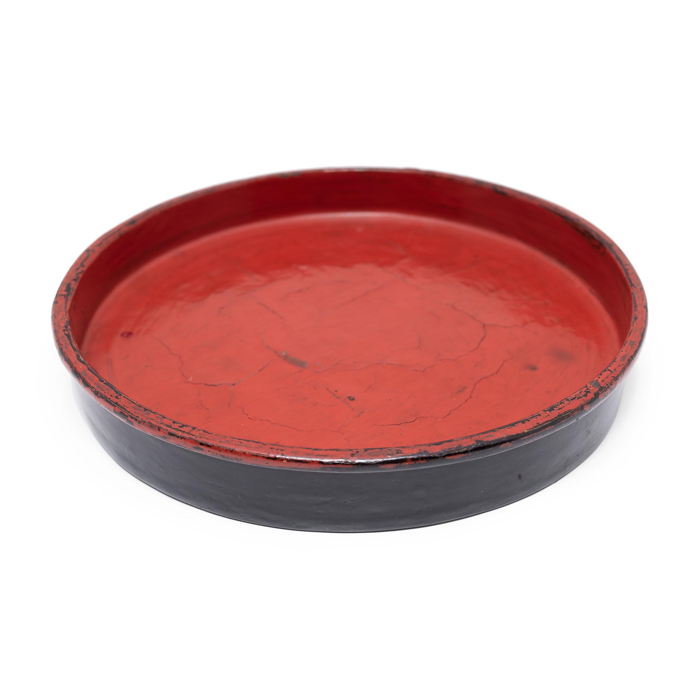 This round tray dates to the early 20th century and is a simple example of Burmese lacquerware. The tray is formed of thin bamboo strips that have been woven and coiled into shape, held in place with a putty of lacquer and sawdust, and finished with