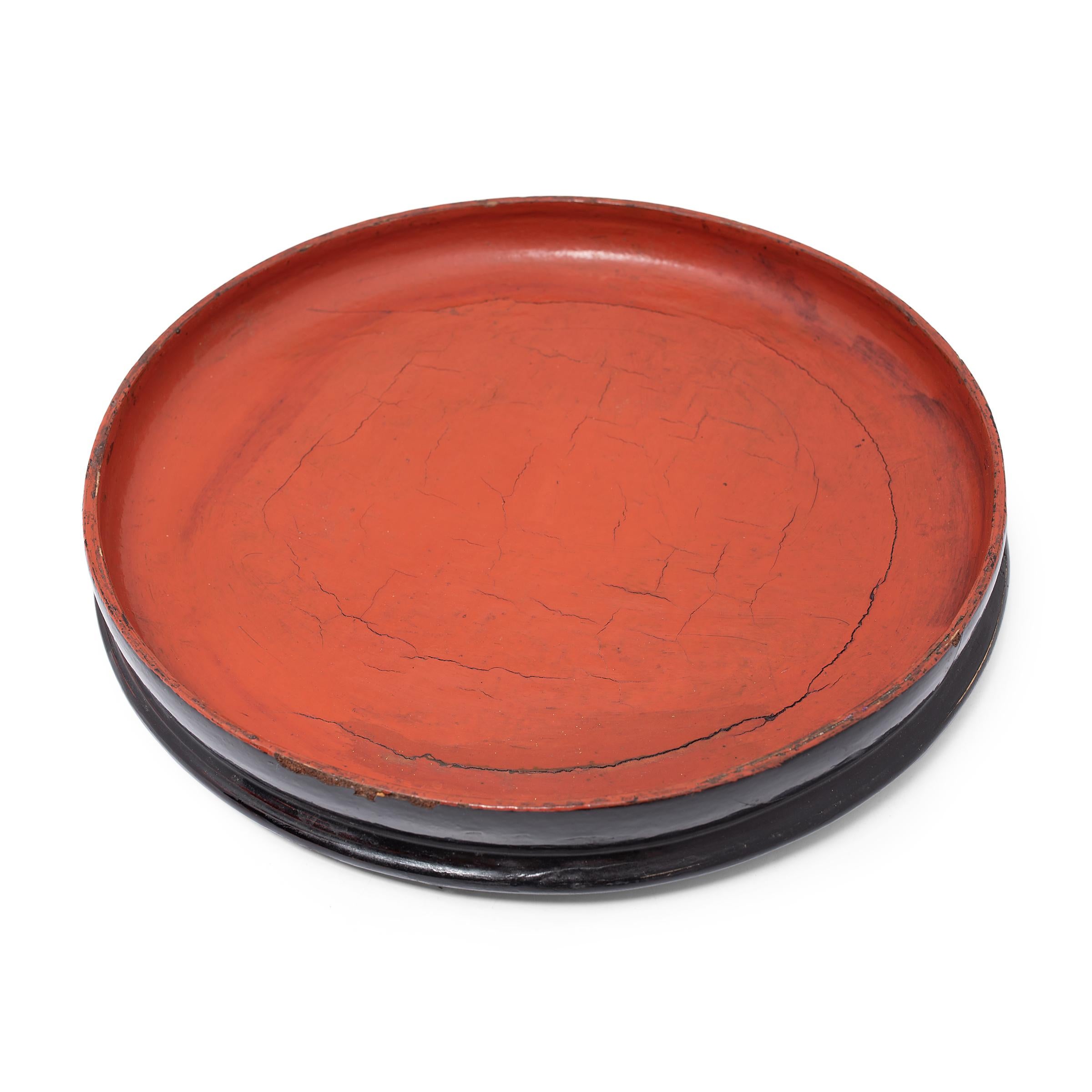 This round footed tray dates to the early 20th century and is a simple example of Burmese lacquerware. The tray is formed of thin bamboo strips that have been woven and coiled into shape, held in place with a putty of lacquer and sawdust, and