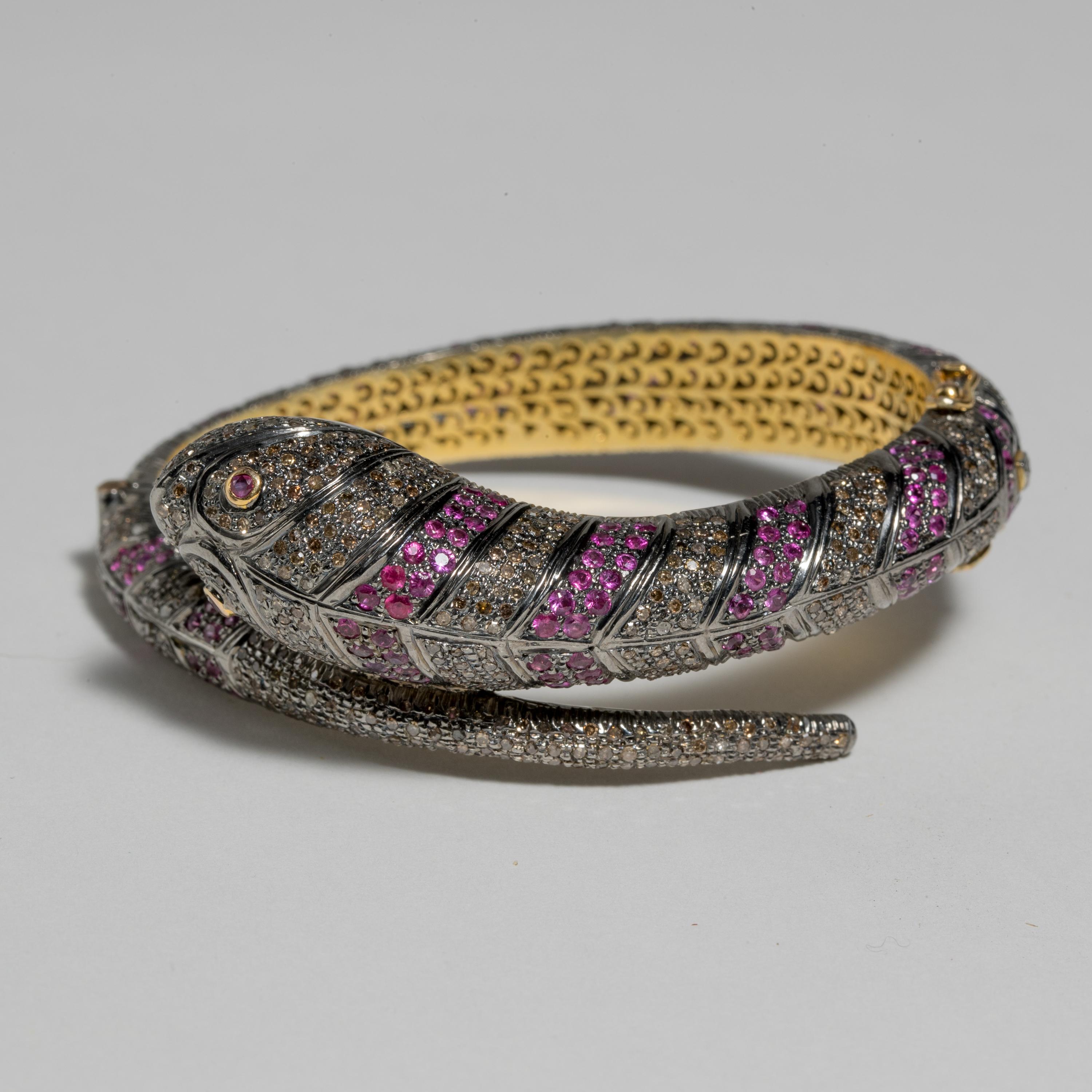 A snake bracelet with faceted Burmese Rubies and Diamonds in a pave` setting.  18K gold and sterling.  Rubies and diamonds are round cuts.  Diamonds total 4.40 carats; rubies are 5.25 carats.  The oval shape keeps the snake head and tail on top of