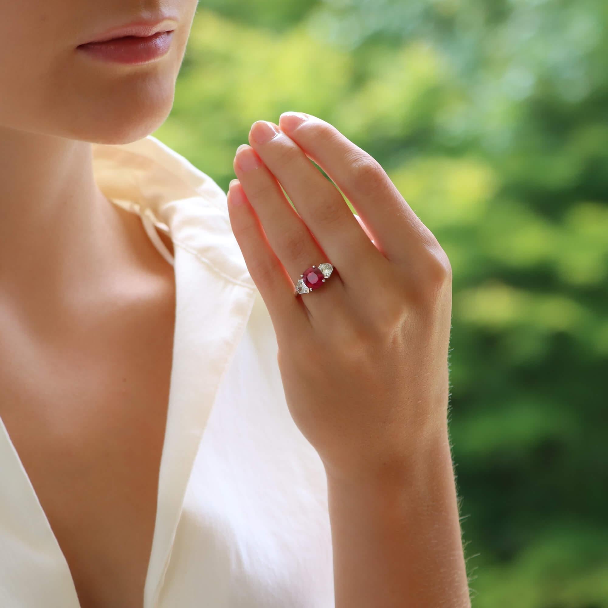A gorgeous Burmese ruby and diamond three stone engagement ring set in platinum. The piece is centrally set with an incredible cushion cut 3.11ct Burmese ruby that has an amazing luscious colour. It is then sided with two trapezoid cut diamonds,
