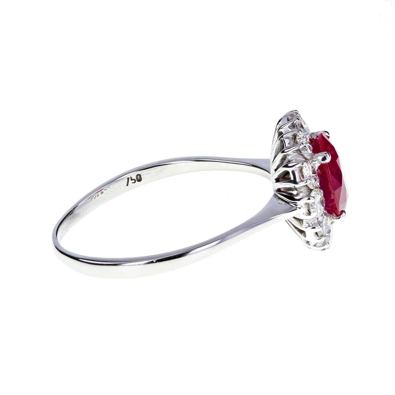 A fine and impressive vintage cluster ring. A central round-cut Burma ruby of deep 'pigeon-blood' colour is surrounded by 12 brilliant-cut diamonds of bright and lively nature, to give a round, daisy-cluster. Plain shank with knife-edge shoulders.