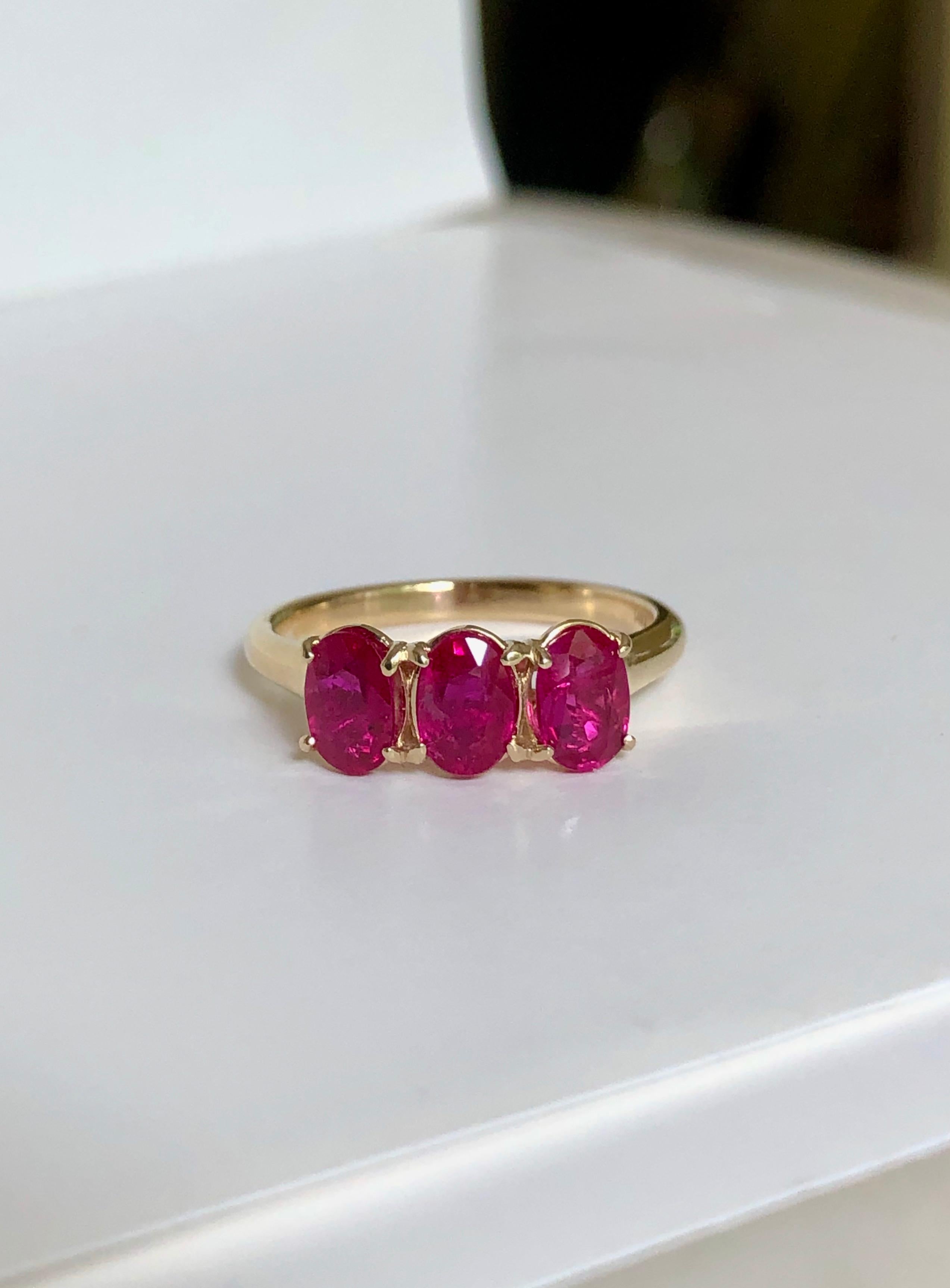 Uno splendido anello trilogy di rubini in oro giallo 14 carati. Disegnato con tre rubini dal taglio ovale e dal colore rosso-rosa. Origine birmana, trattamento termico. 6,4 mm x 4,5 mm circa. Peso totale dei rubini: 1,72 carati circa. Peso: 3,34