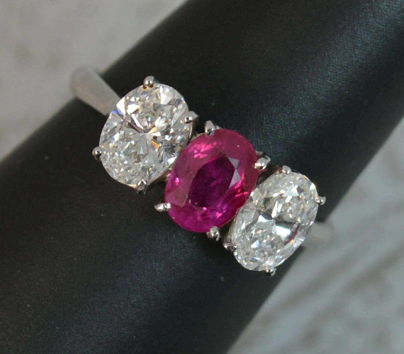 A superb Ruby and Diamond trilogy ring in 18ct White Gold.
Designed with an oval cut ruby to centre, vivid pink red colour. Burmese origin, heat treatment. 6.3mm x 4.7mm approx. To either side are oval cut diamonds, vs clarity, e-f colour, very