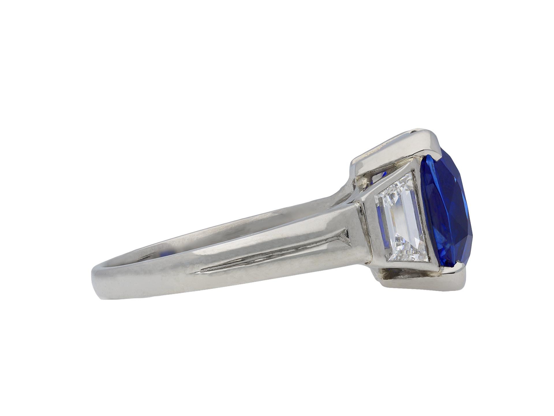 Burmese sapphire and diamond ring. Set with a cushion shape old cut natural unenhanced Burmese sapphire in an open back four claw setting with an approximate weight of 3.70 carats, flanked by two tapered baguette cut diamonds in open back rubover