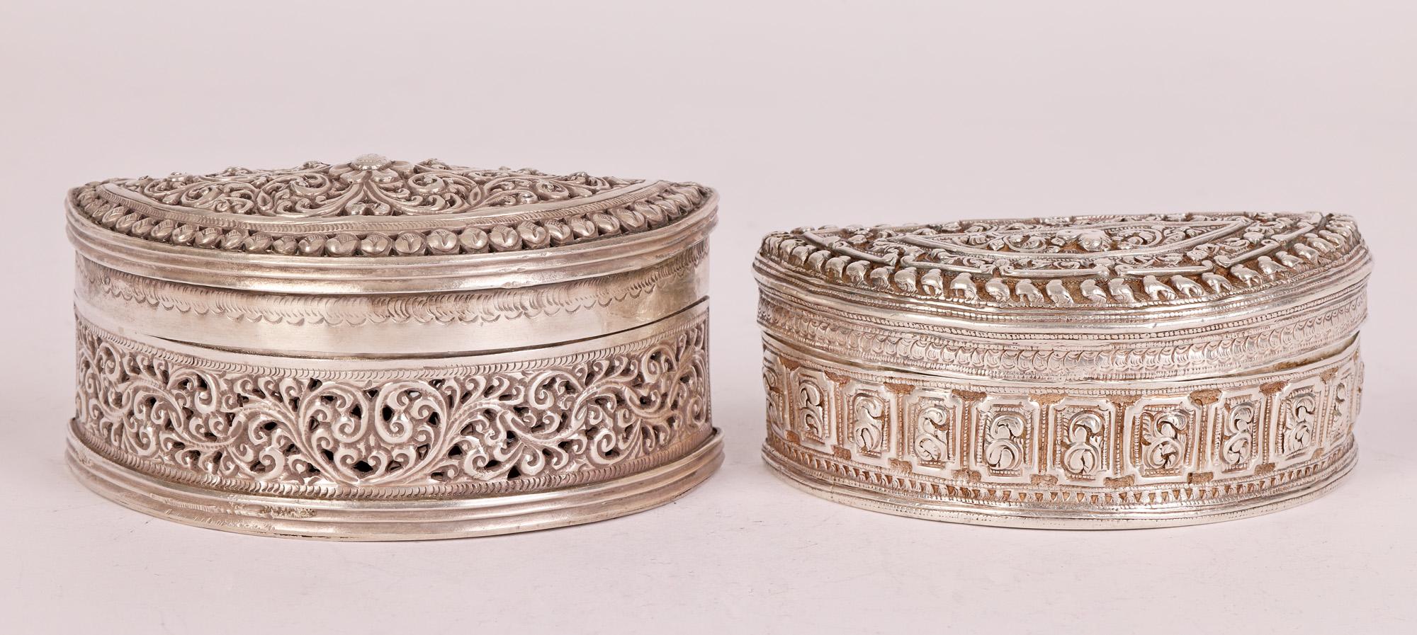 Two antique Burmese silver Betel boxes of half moon shape one with a pierced scroll leaf design and the other with embossed patterning with a small lion dog to the cover dating from the 19th or early 20th Century.

The boxes were used to hold and