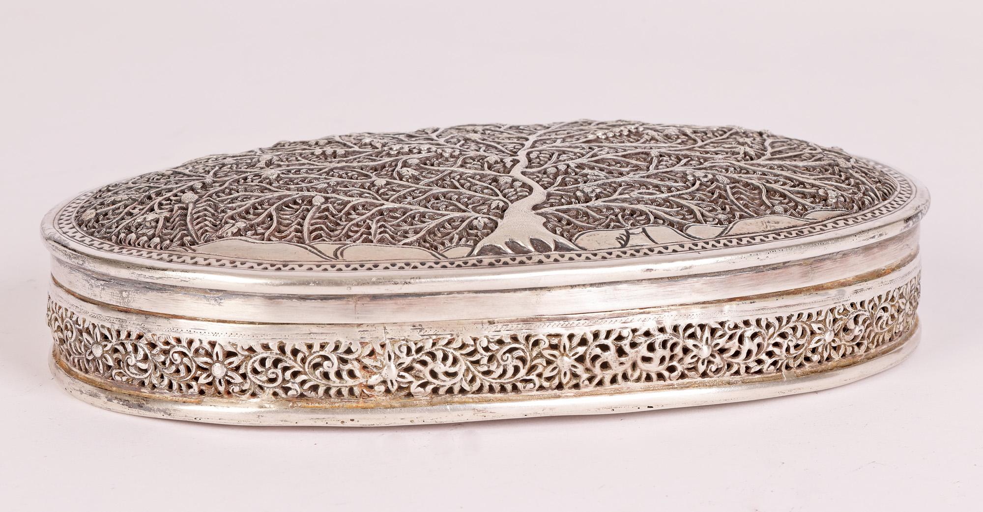 An unusual and very fine antique Burmese silver oval box the cover decorated with a Tree of Life probably dating from the early 20th Century. The box is of flat oval shape with finely pierced cover and sides standing on a flat base. The hinged cover