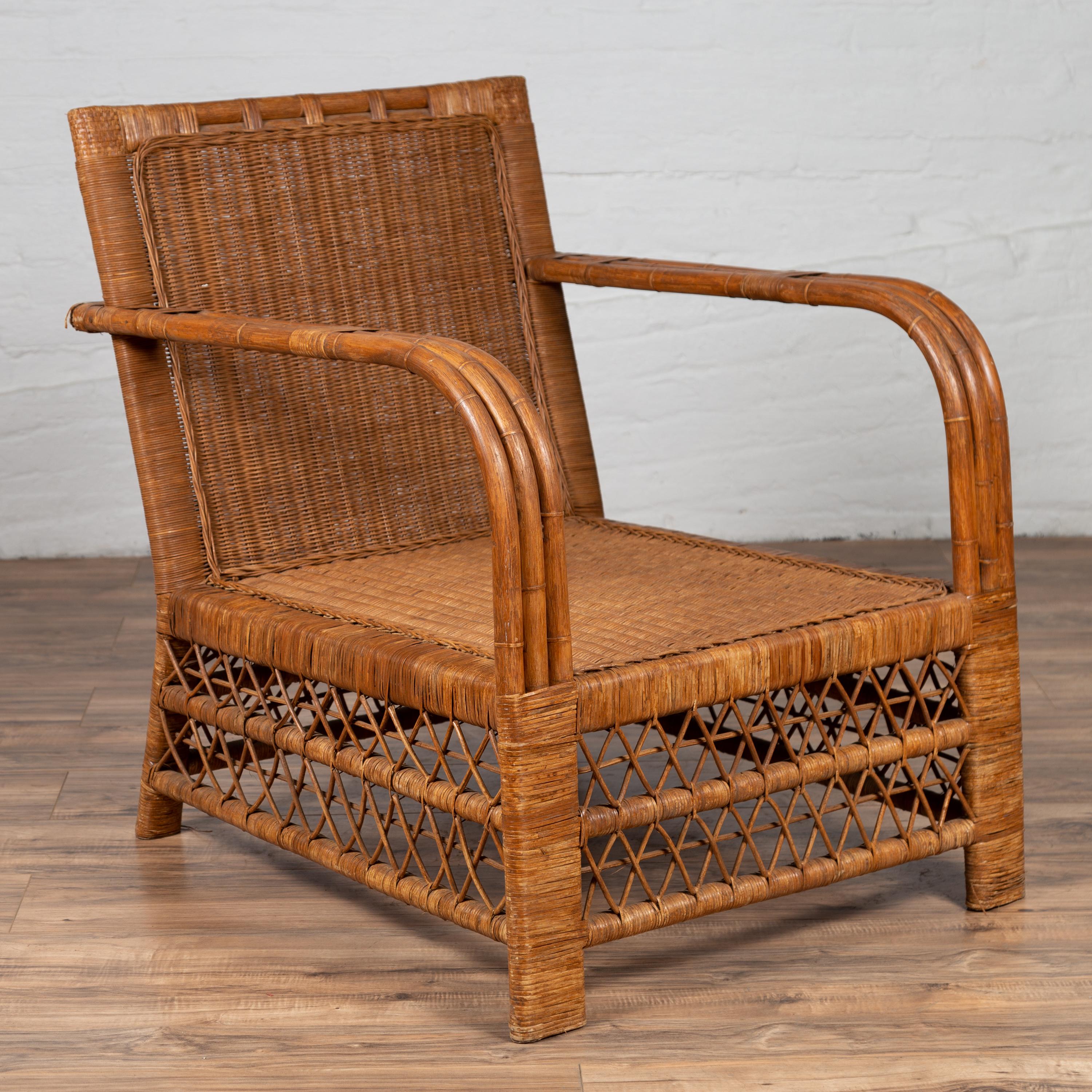 A Burmese vintage plantation lounge chair from the mid-20th century, made of bamboo and rattan. Born in Burma during the mid-century period, this charming plantation lounge chair features a slightly slanted back, connected to two large open arms