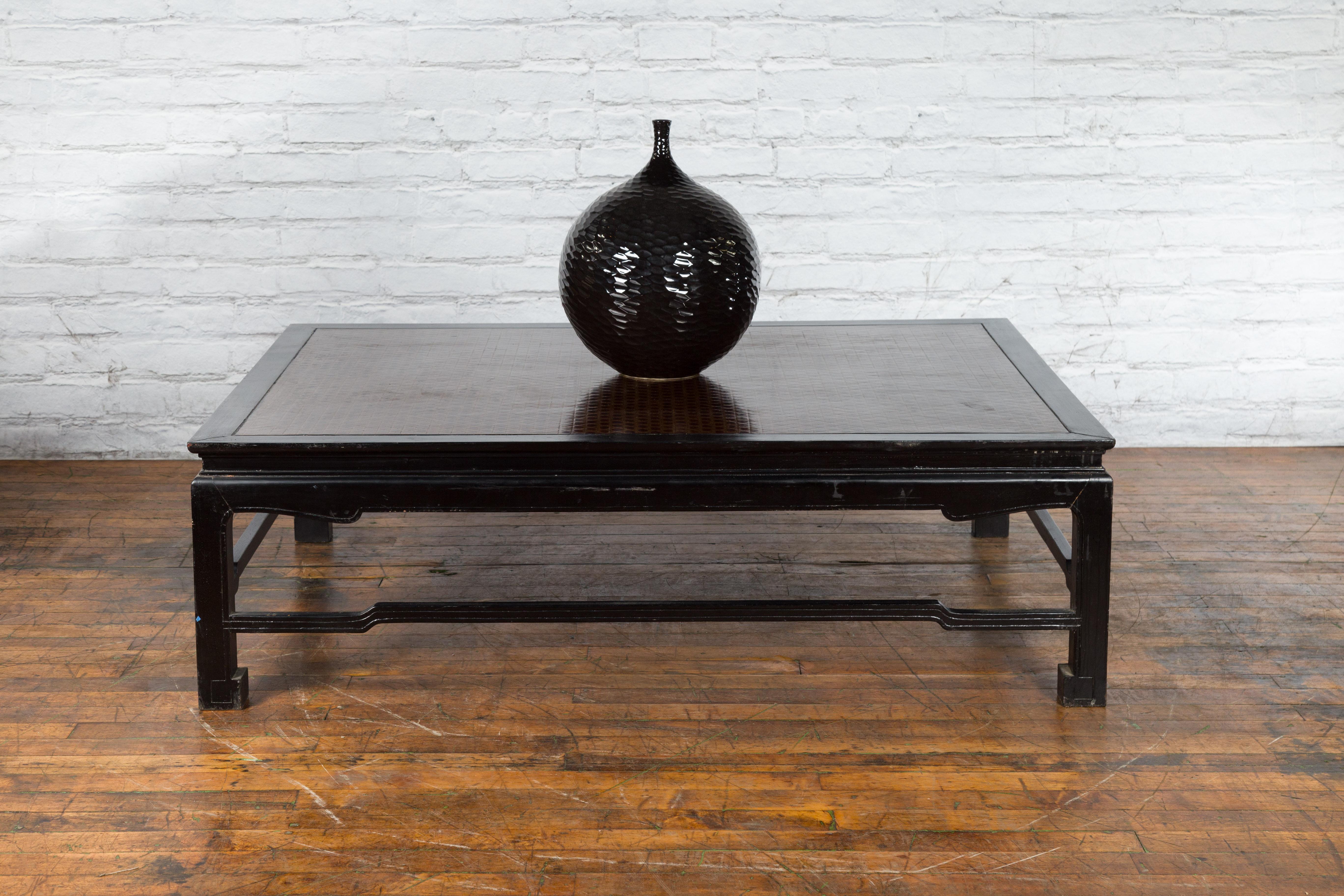 A vintage Burmese coffee table from the mid 20th century with black lacquer body, Negora lacquer inset top, horse hoof feet and humpback stretchers. Created in Burma during the Midcentury period, this vintage coffee table features a rectangular