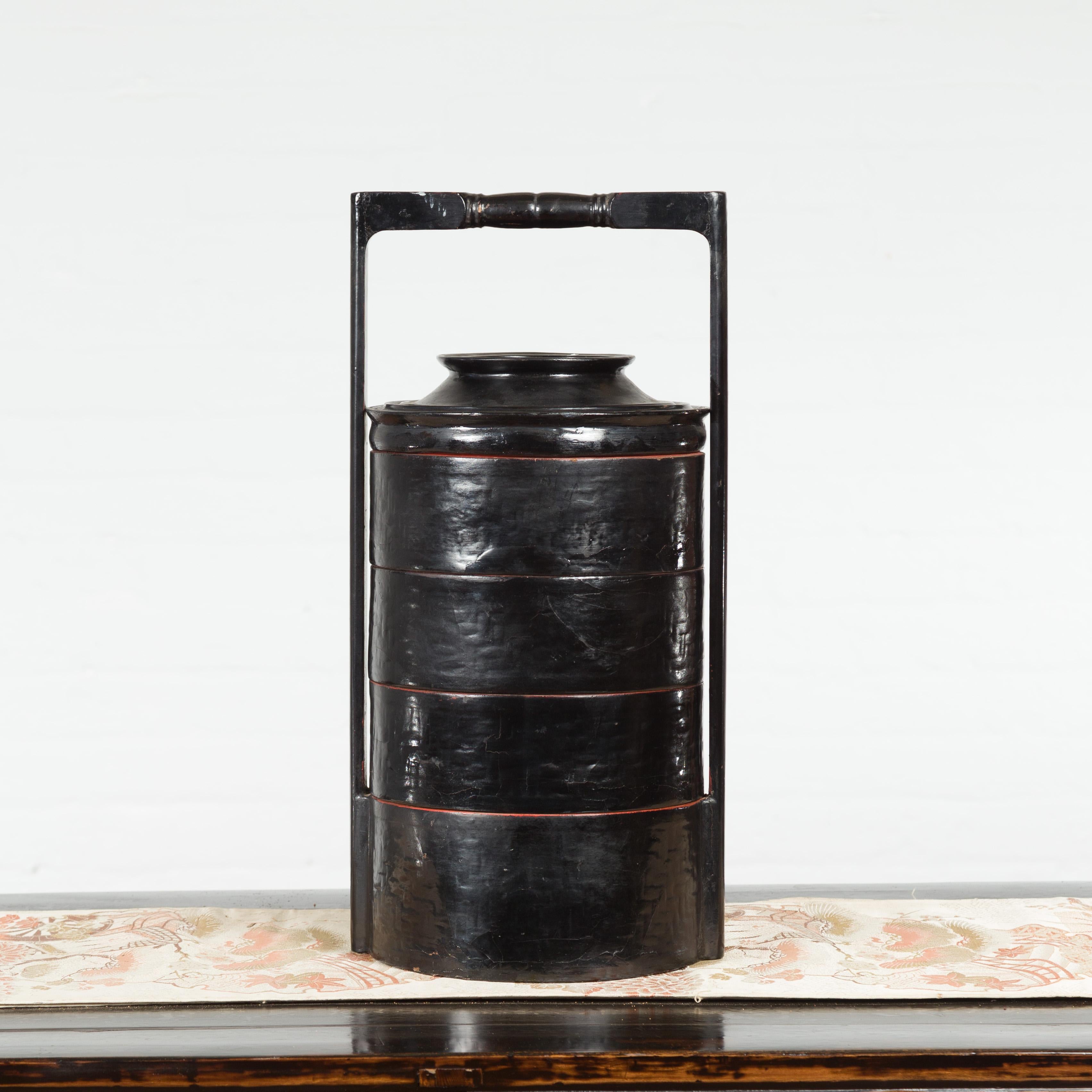 A Burmese vintage black lacquered picnic basket from the mid 20th century, with large handle, seven individual compartments and lid. Created in Burma during the midcentury period, this picnic basket features a circular black lacquered body made of