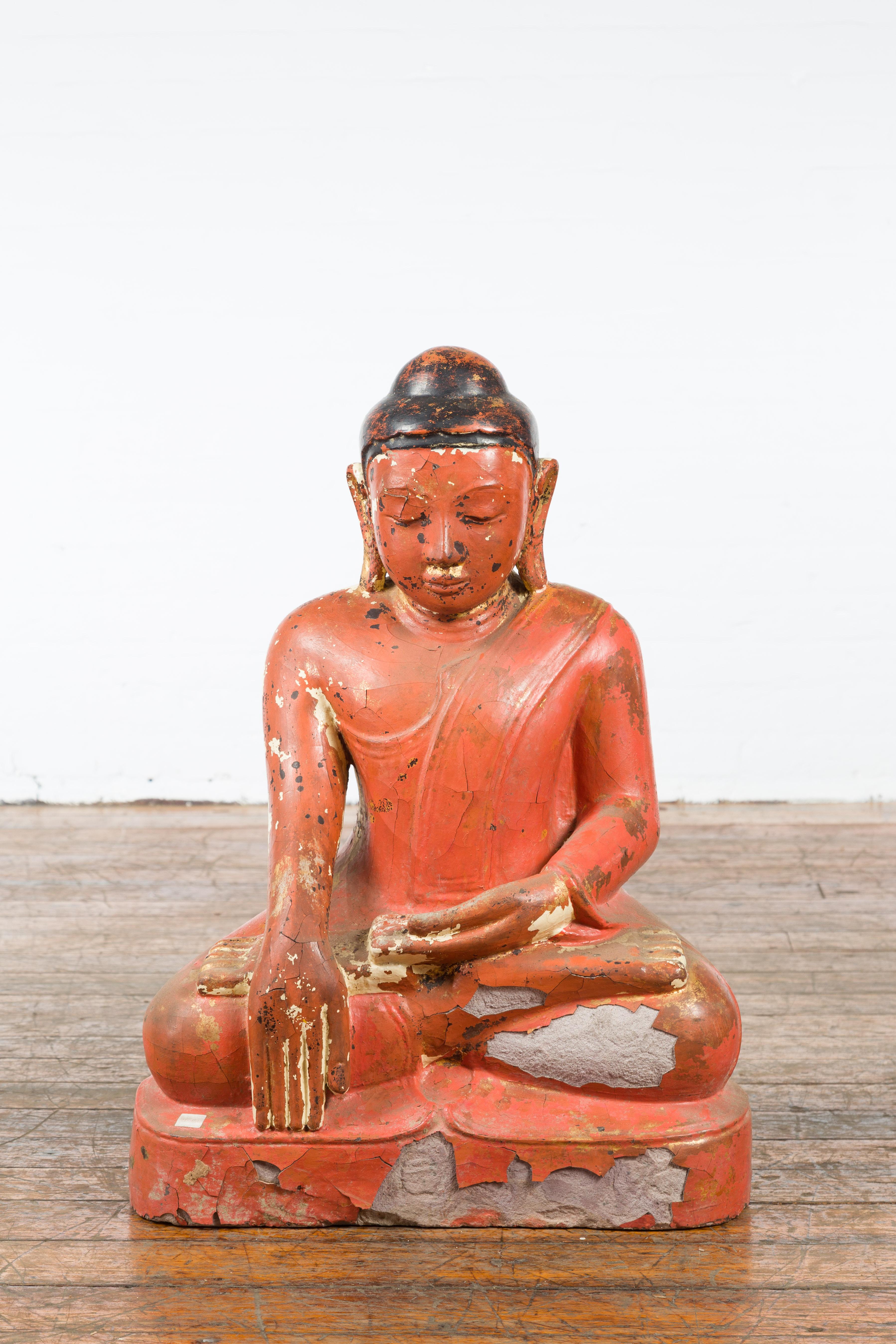 A Burmese vintage lacquer over stone seated Buddha Calling the Earth to Witness from the mid 20th century, with great wear. Created in Burma during the midcentury period, this Buddha sculpture, sold as is, charms us with its nicely weathered patina