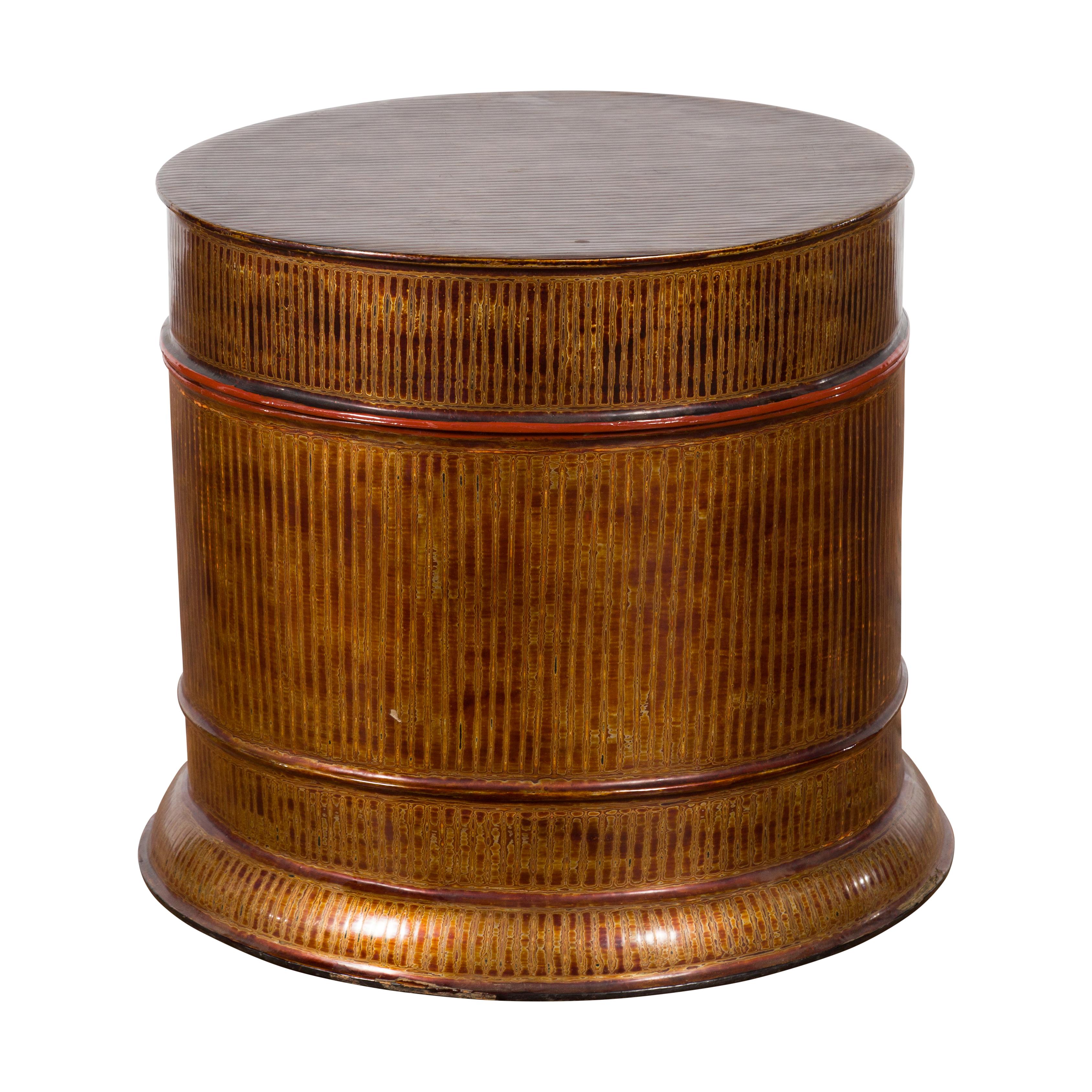 A vintage Burmese negora lacquer round storage bin box from the mid-20th century, with vertical stripes. Created in Burma during the 20th century, this large decorative box features a negora lacquered body resting on a circular base. Showcasing red