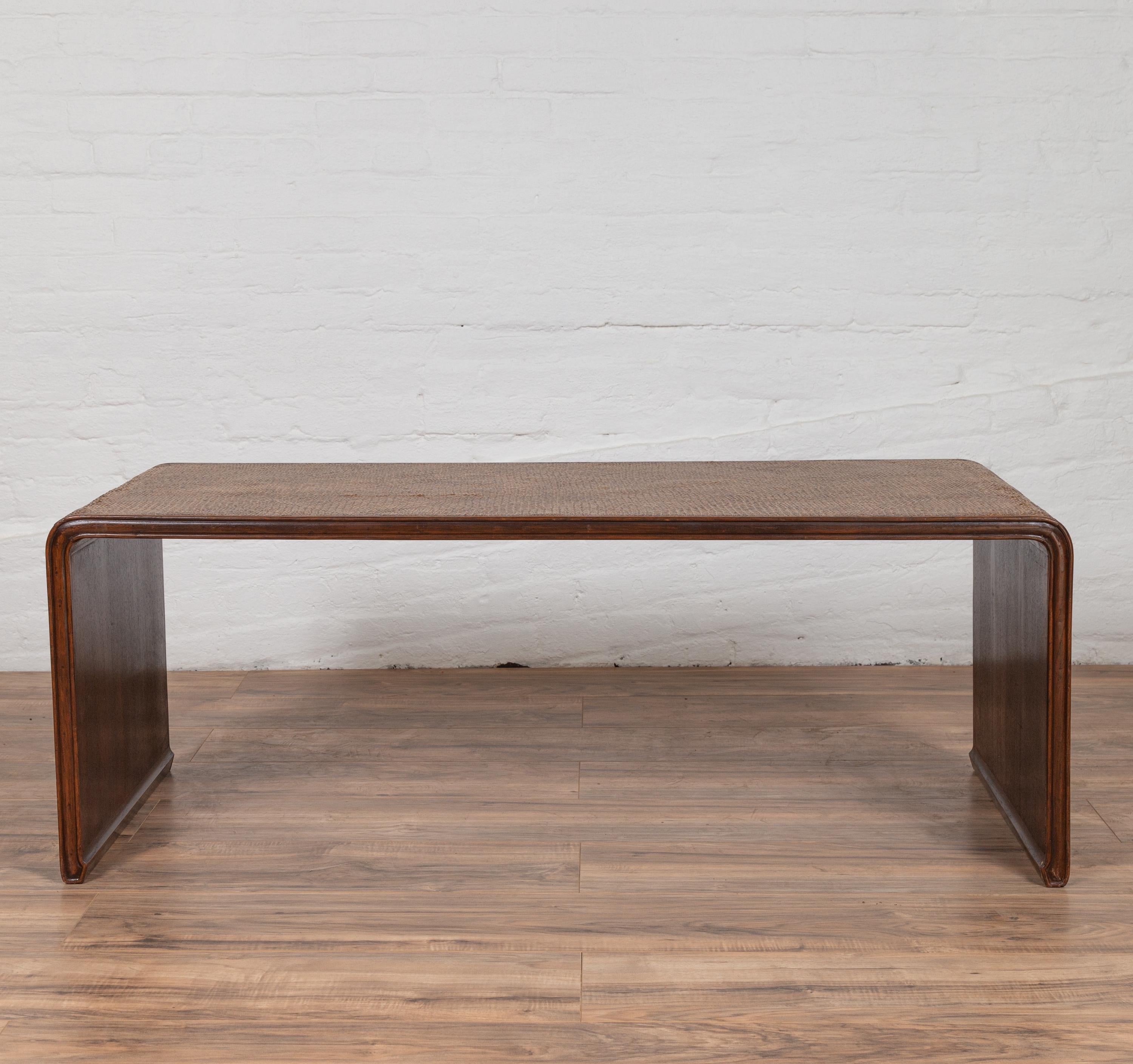 A Burmese vintage rattan waterfall coffee table with contemporary design from the mid 20th century, mounted on a wooden frame. This simple yet elegant Burmese low console table features a clean silhouette, presenting a waterfall wooden frame