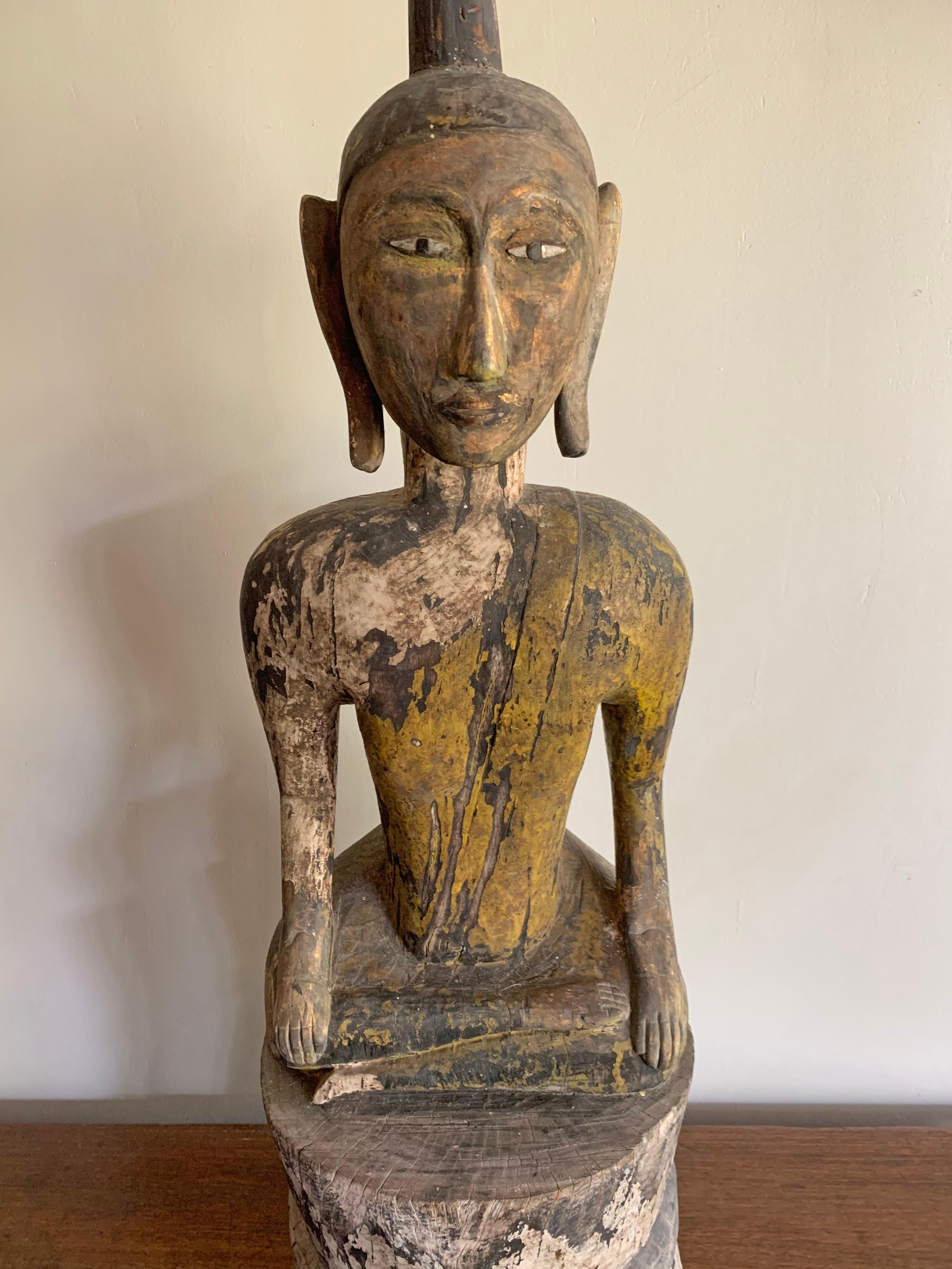 This buddha is a hand-carved from wood and originates from Burma, modern day Myanmar. It once featured an elaborate lacquer finish, however much of this has worn away over the decades. There are traces of the original black and yellow lacquer. The