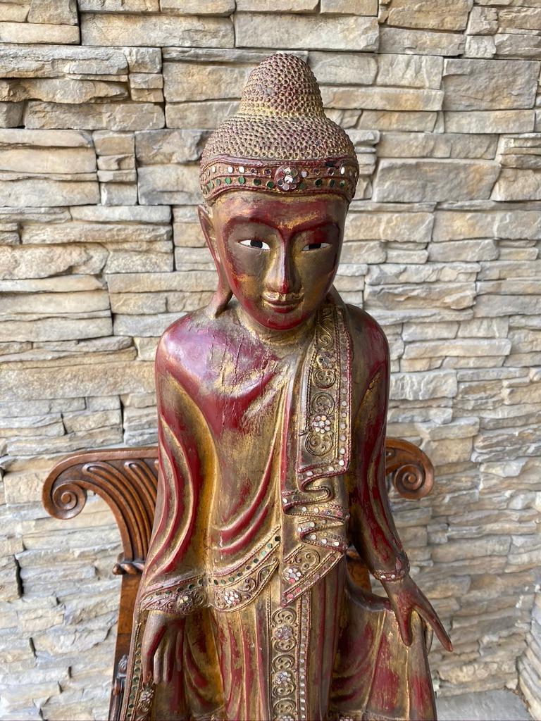 The Burmese handcrafted wooden Buddha is red lacquered 