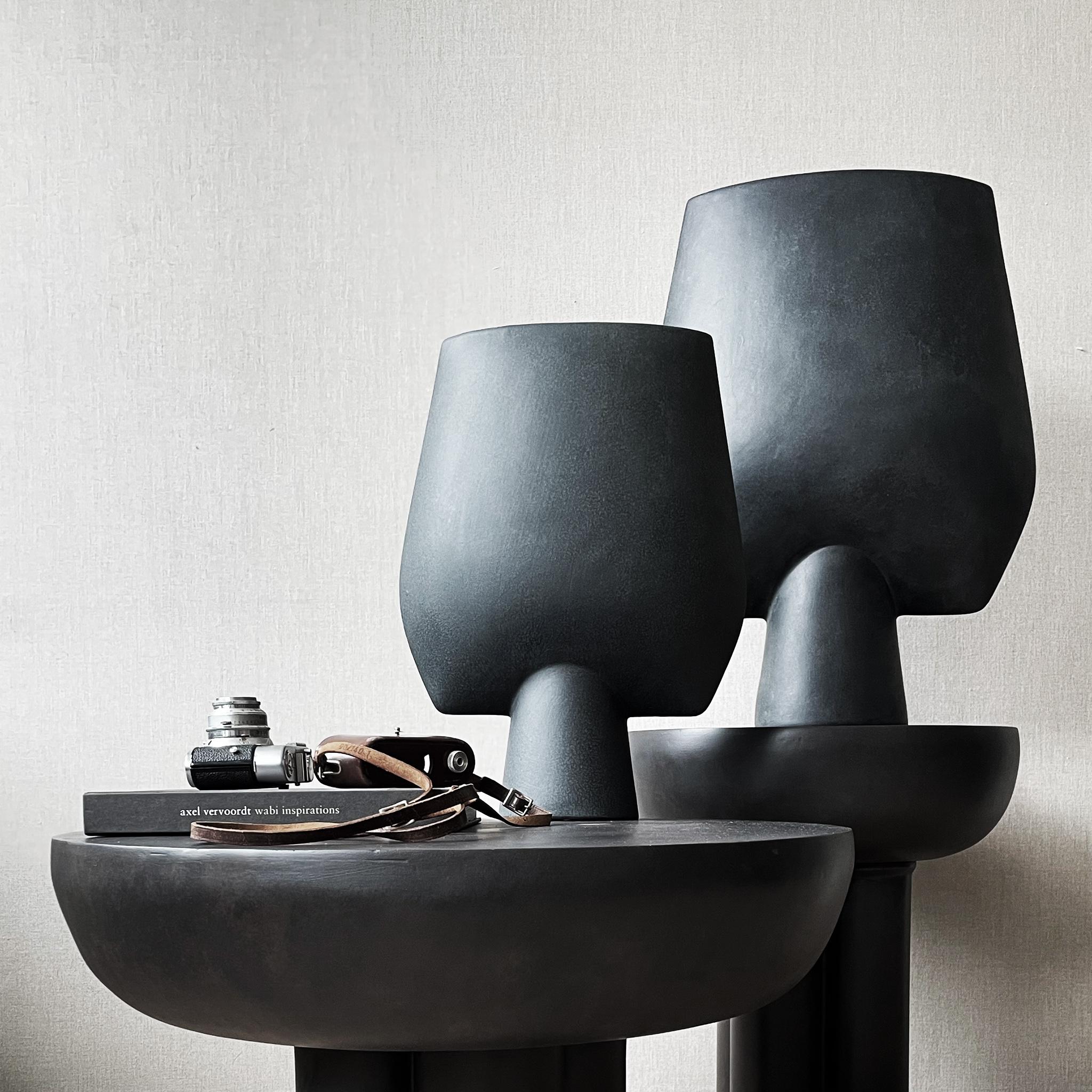 Burned black crown table tall by 101 Copenhagen
Designed by Kristian Sofus Hansen & Tommy Hyldahl
Dimensions: L 45 / W 45 /H 50 cm.
Materials: fiber concrete

The collection of tables entitled Crown is cast in one piece formed as a circular
