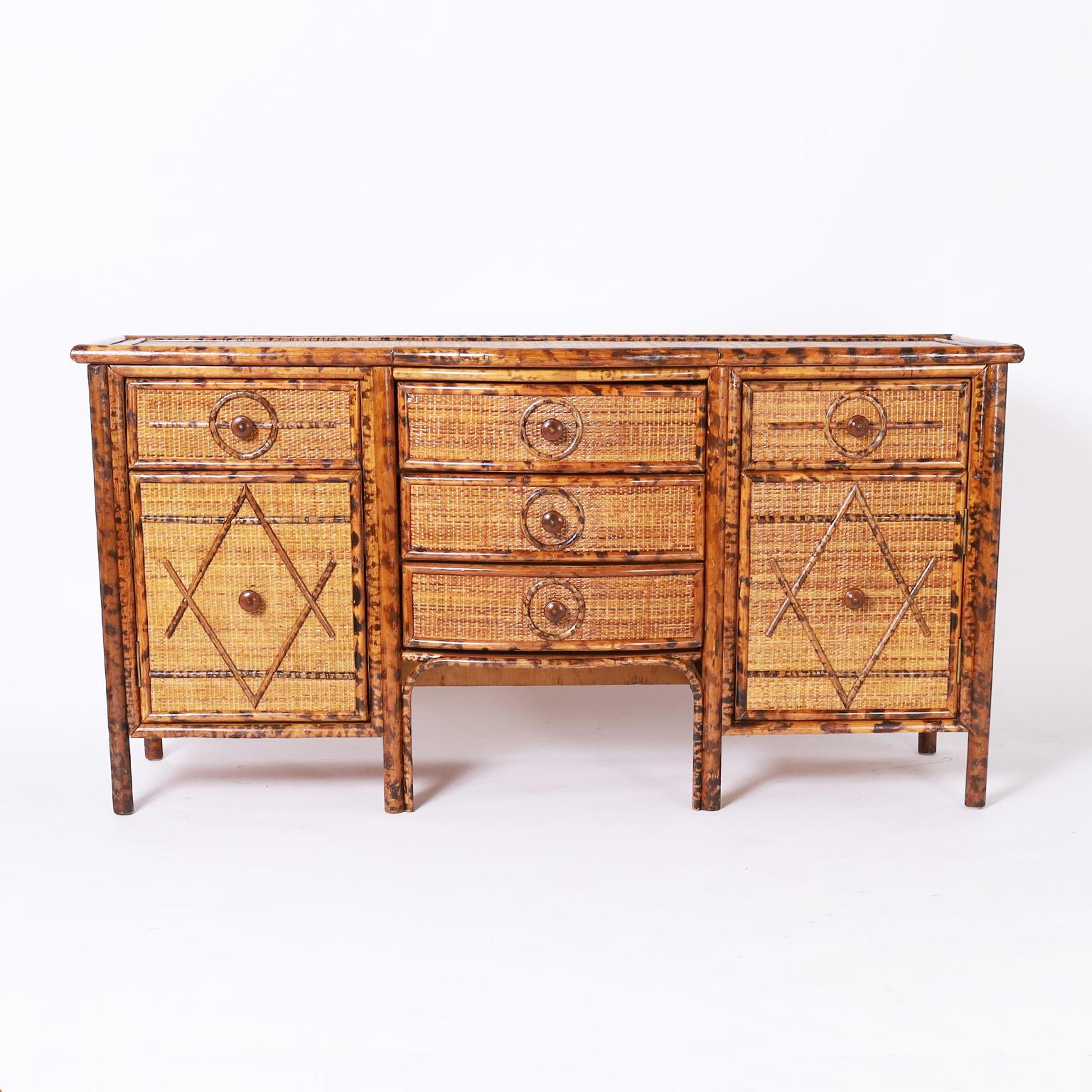 British colonial style bow front buffet with plenty of storage and high decorative appeal having a burnt bamboo frame and grasscloth panels all around under geometric bamboo designs.