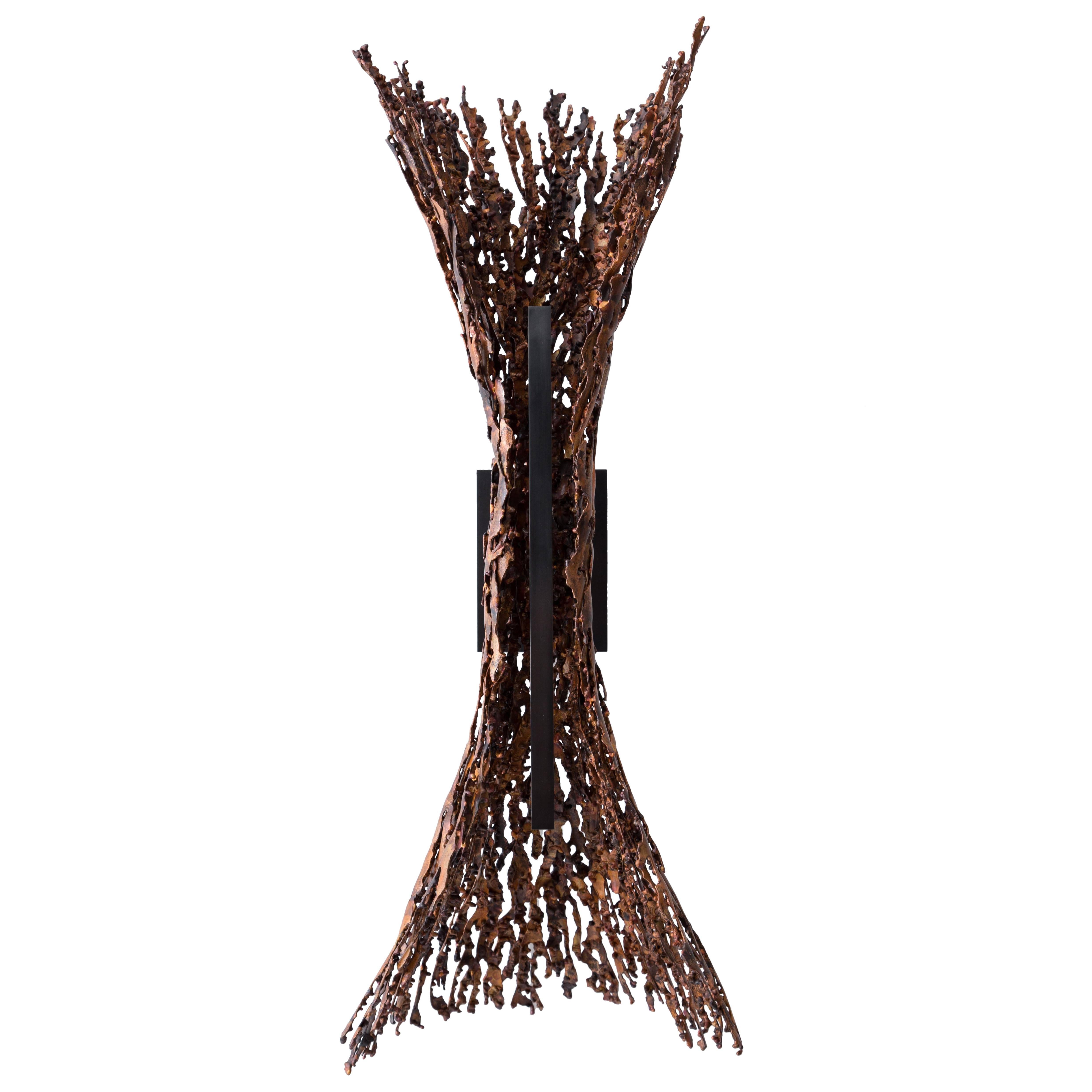 The burnt copper form sconce makes a bold statement. The body of the light is hand assembled from heat-formed copper pieces into a dramatic flaring shape that has the organic quality of something found in nature. The meandering edges and varying