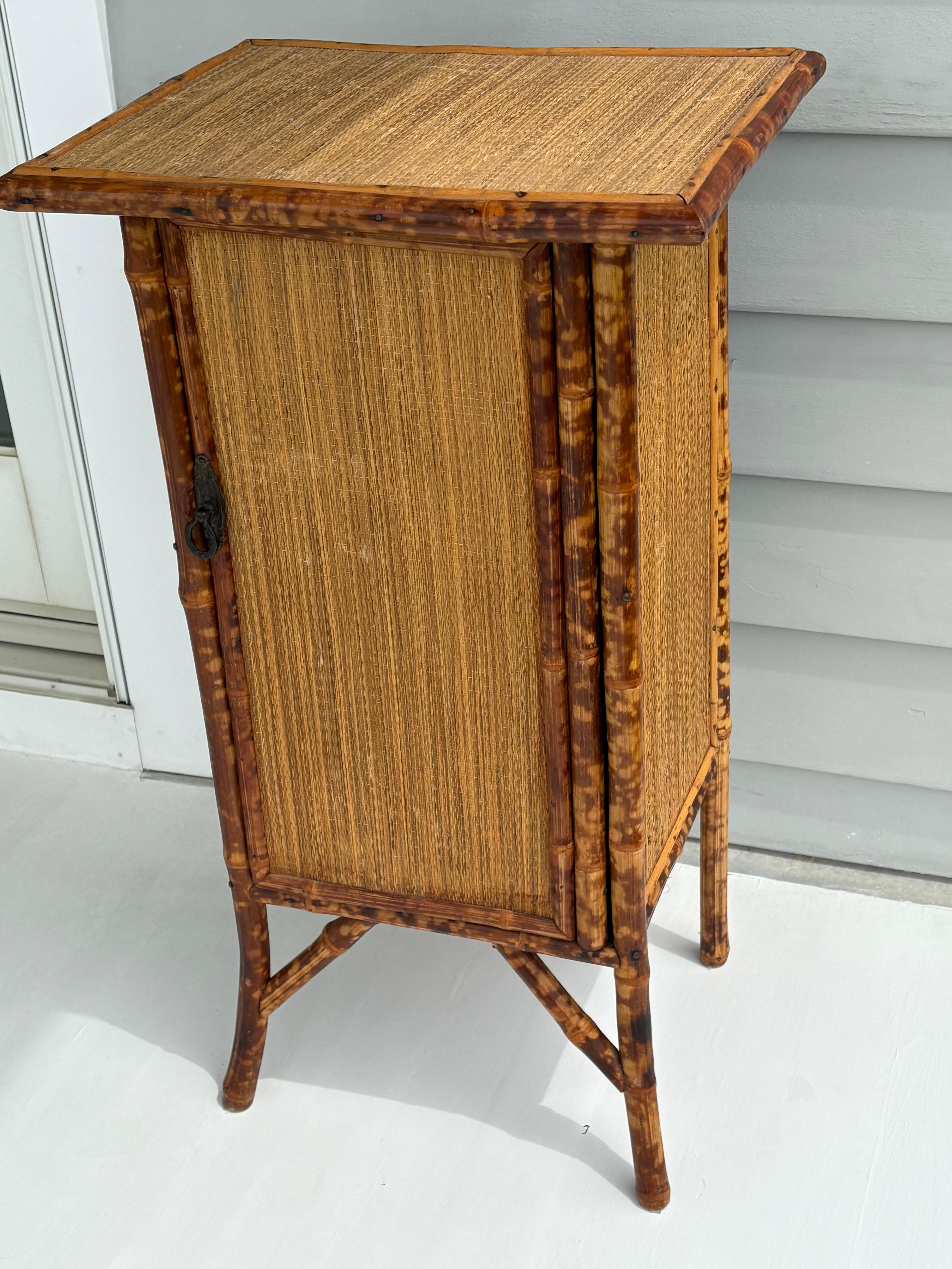 Precioso armario de bambú con tela de hierba y carey . El armario se abre y cierra suavemente con una sola balda fija . Queda muy bien como mueble en tu salón o puede estar en tu dormitorio como mesilla de noche . Muy buen estado general . El