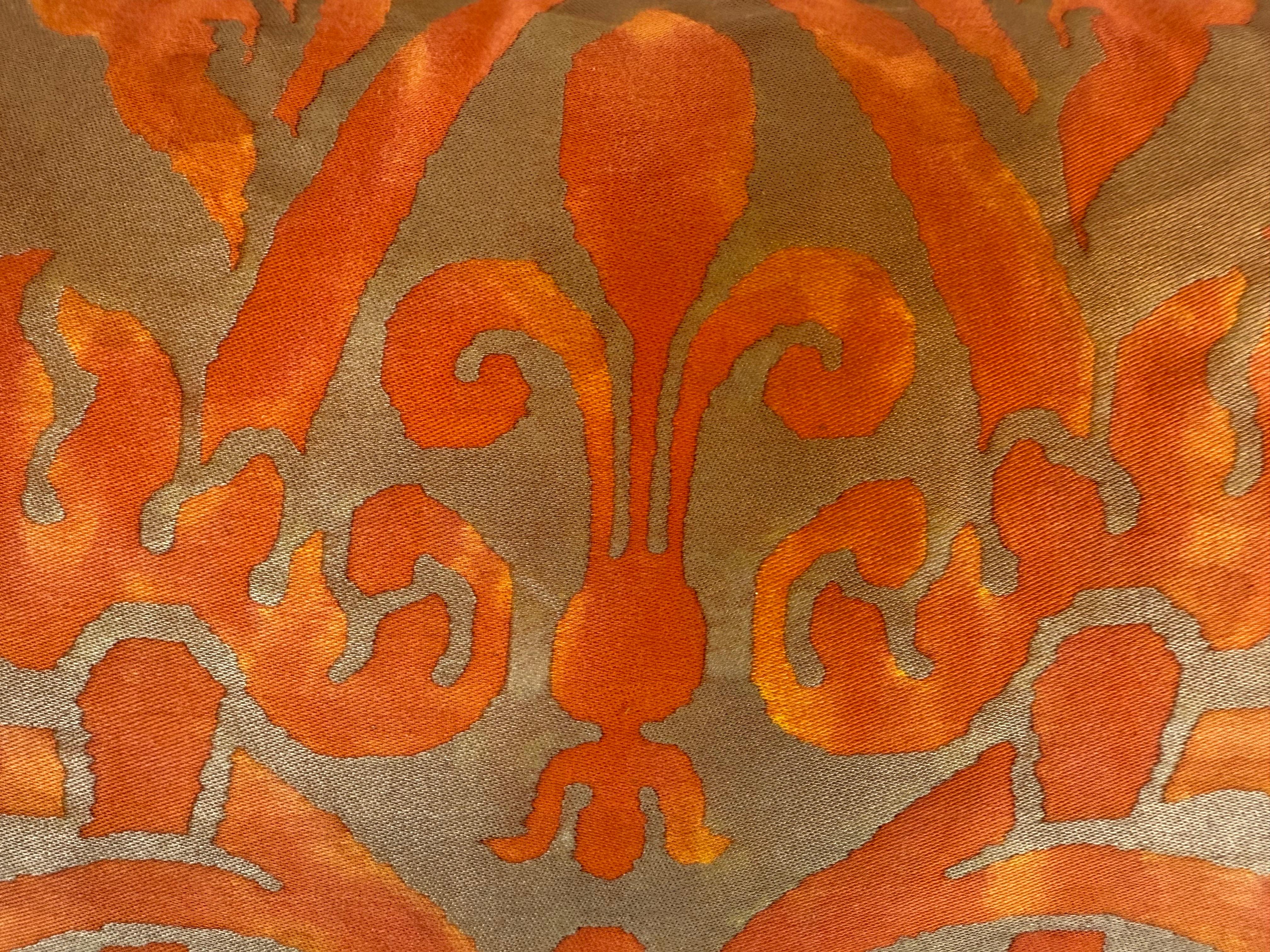 Questo cuscino audace e sorprendente è realizzato in un tessuto Fortuny con un ricco motivo damascato arancione bruciato su uno sfondo dorato.  Il design mette in mostra fiori e volute stilizzati e sovradimensionati con un effetto pittorico, quasi