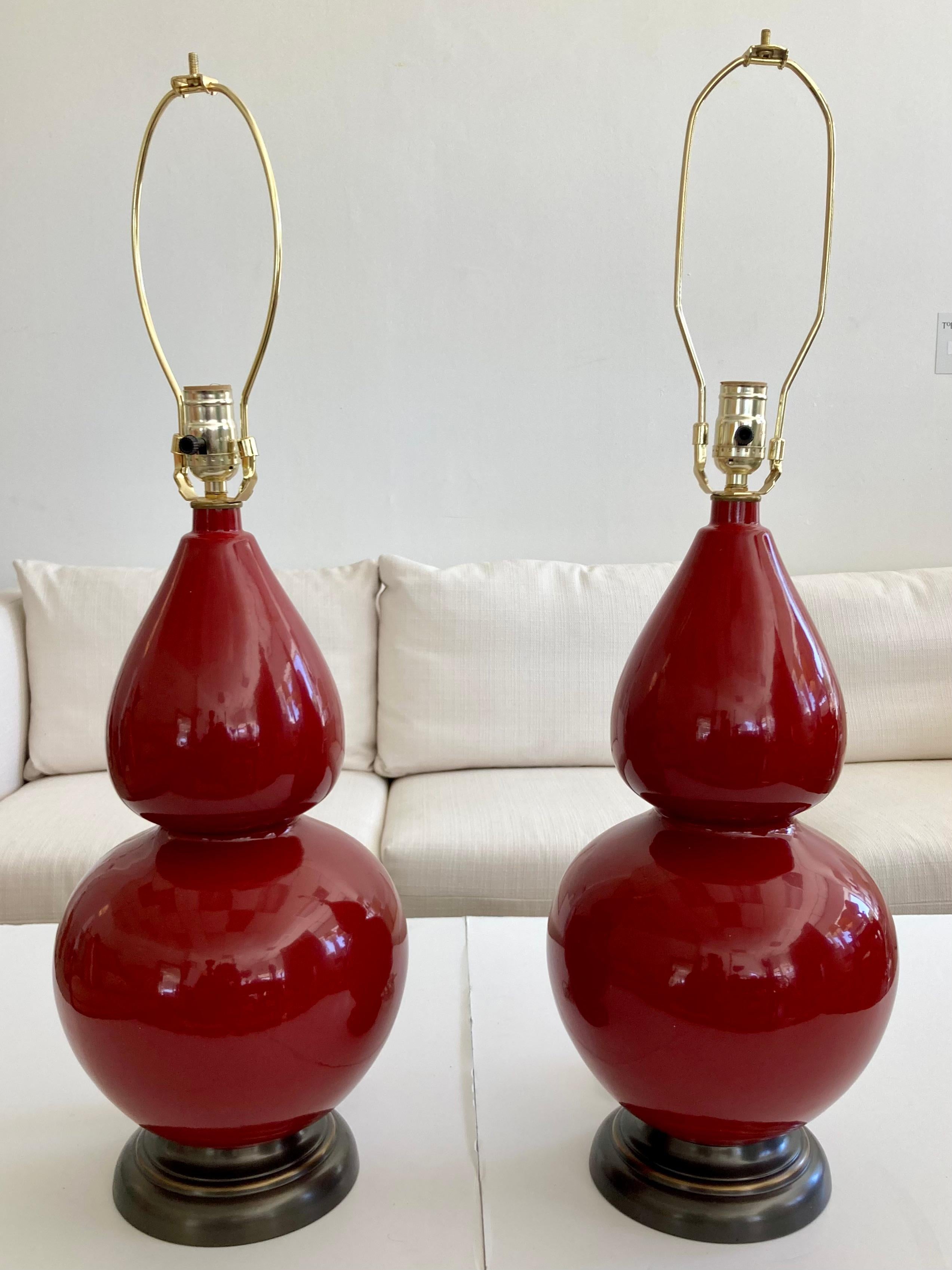Pair of burnt red glazed ceramic gourd table lamps. Beautiful color old par with previous repair on some chips. Luckily they are towards the back of the lamps, see photos. Beautiful shape and hardware fitting, and aged metal base. Add your favorite