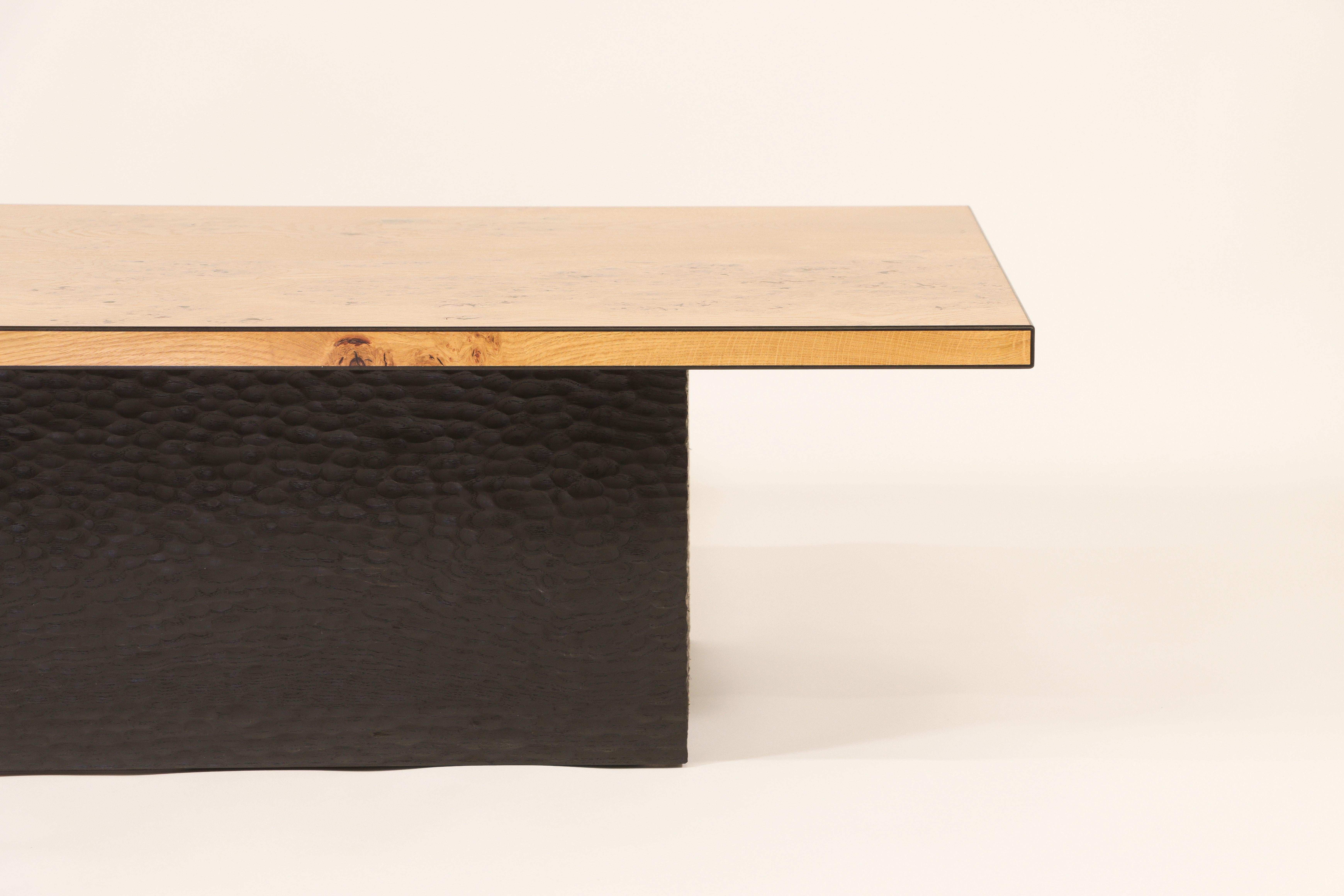 The tabletop is constructed from 450-year-old burr oak from Sutherland in Scotland and has African black ebony inlay banding around all the edges. The base is solid ash with a hand-carved textured surface that has been ebonised black. This table is