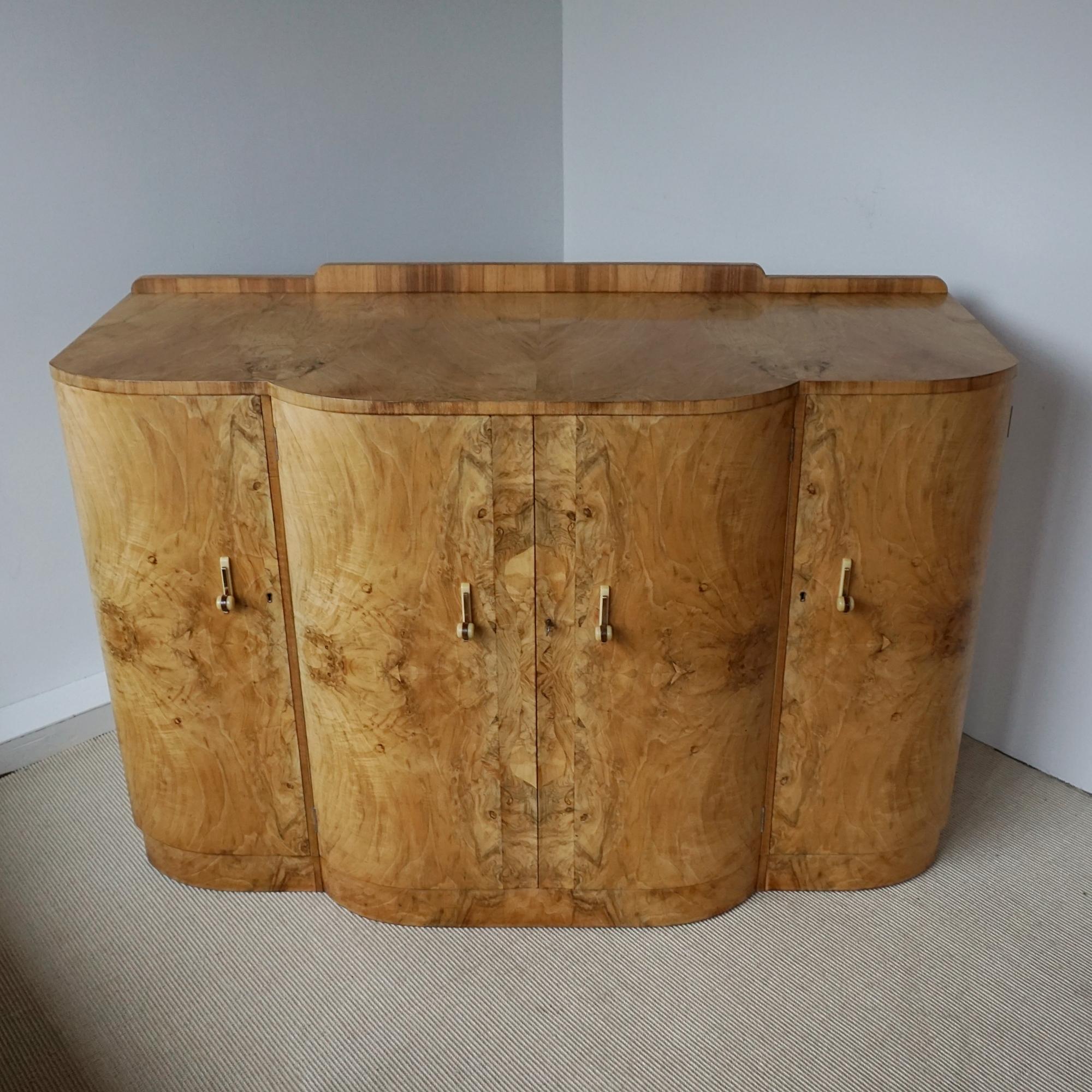 Ein Art-Déco-Sideboard von Harry & Lou Epstein. Drei zentrale Schubladen mit geschwungenen Türen aus Wurzelnussholz, flankiert von zwei Regalfächern mit Fronten aus Wurzelnussholz. Oberseite aus Wurzelnuss furniert, Seiten und Zierleisten aus