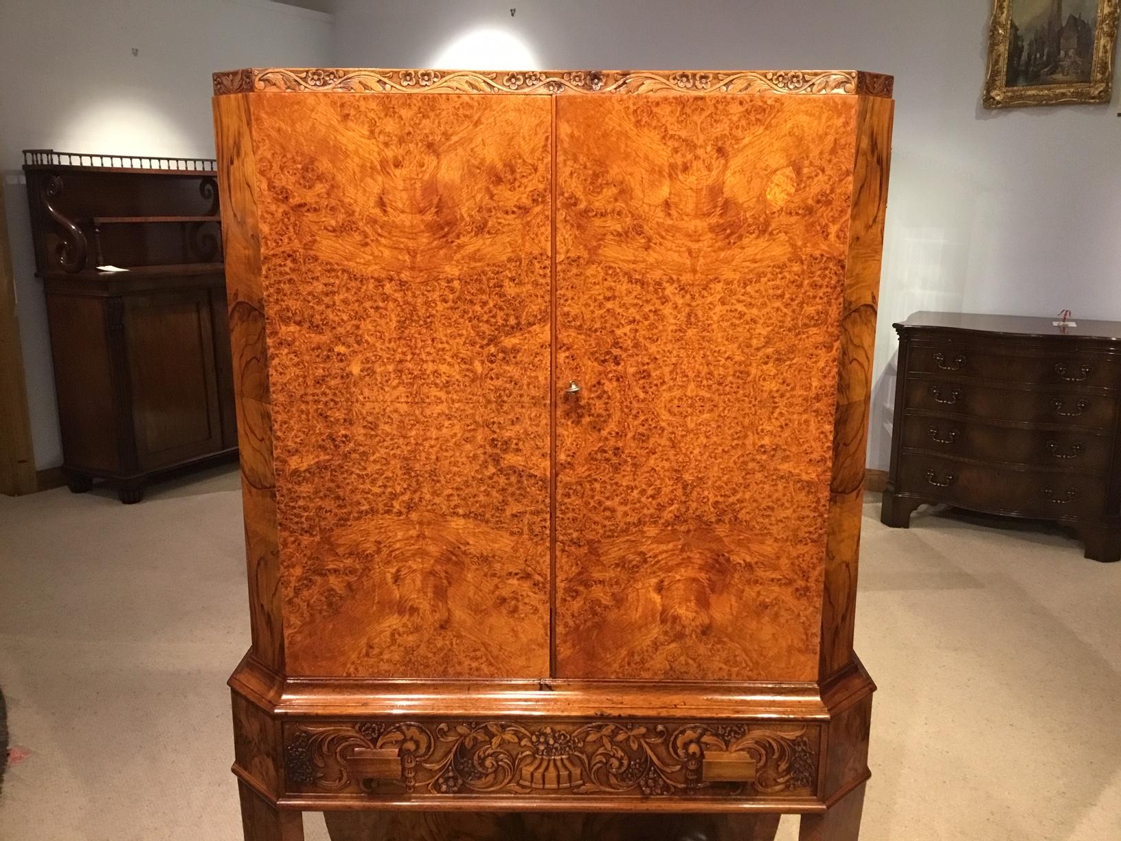 A stunning quality burr walnut Art Deco Period antique cocktail cabinet. The upper section with a rectangular top veneered in burr walnut with canted corners and a finely carved moulded edge, above the twin shaped doors veneered in the finest burr