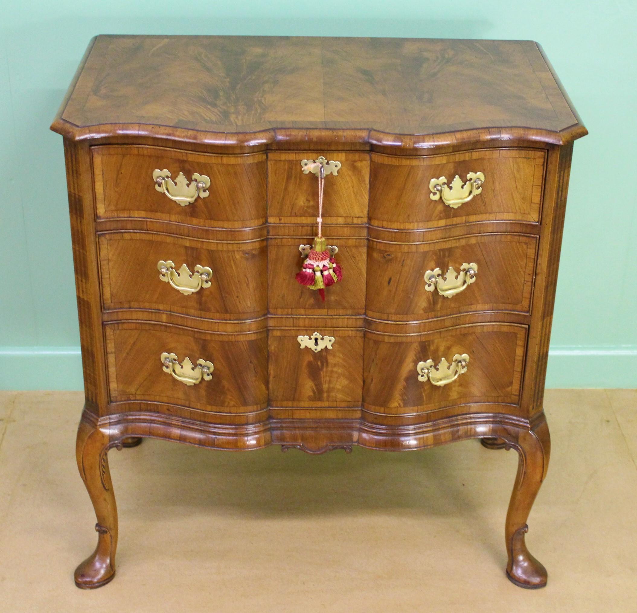 The finest quality burr walnut chest of drawers by the renowned maker Charles Tozer of London. Of serpentine form and cross banded throughout. With a series of 3 graduated drawers fitted with their original solid brass hardware. With canted corners