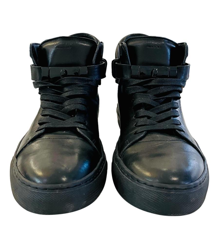 Buscemi Leather High-Top Sneakers With Padlock Detail
Black lace-up sneakers designed with round toe and strap around the ankle.
Detailed with black 'Buscemi' engraved padlock to rear and leather clochette to the side and featuring logo embossment