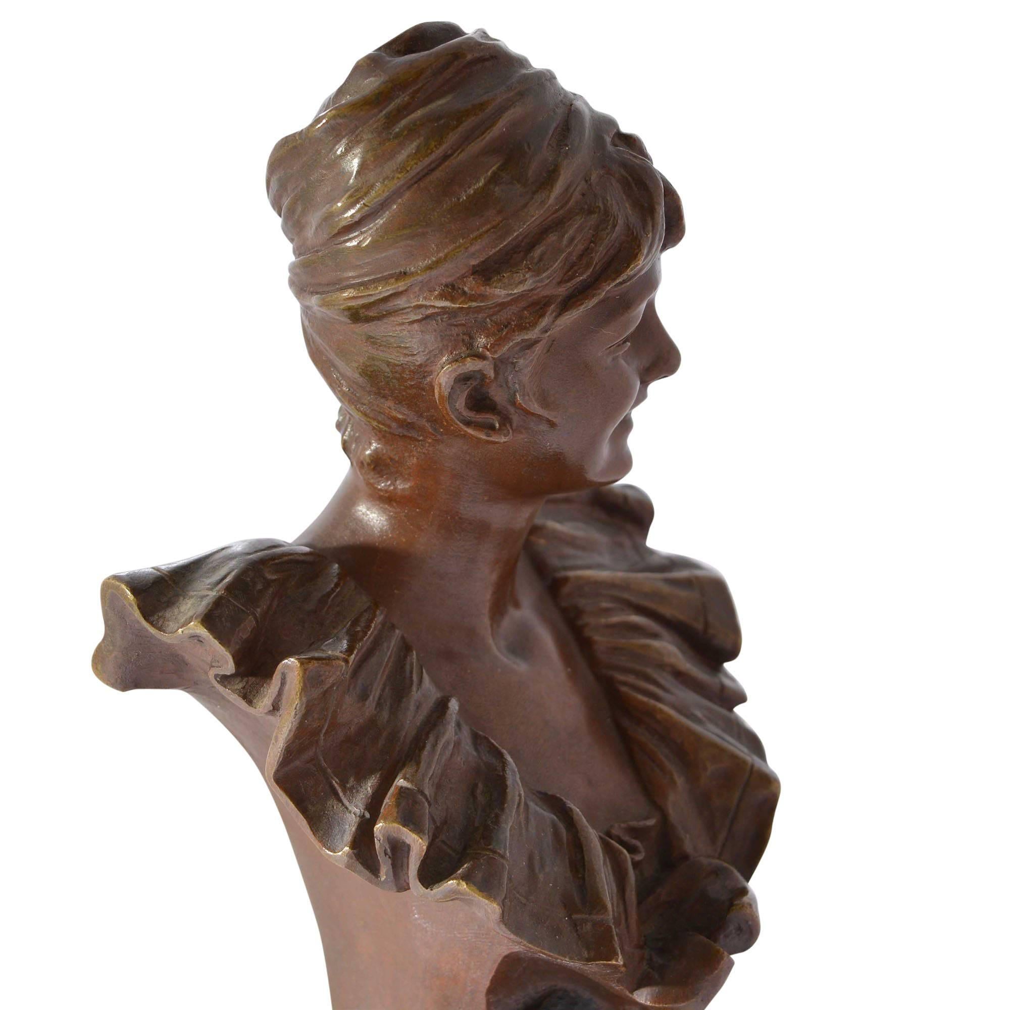 A cast by Societe des Bronzes de Paris from the model bust titled Pierrette by Belgian artist George Van der Straeten (1856-1928). This signed sculpture features a joyful young woman with a detailed ruffled collar top. Her hair is up and she wears a