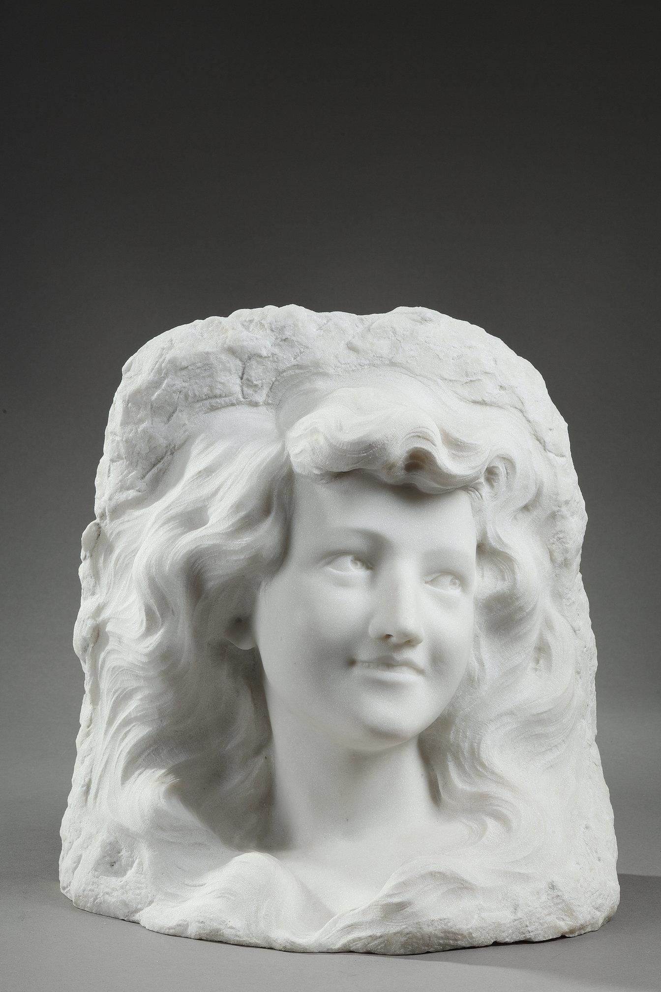 Direct carving of a portrait of a smiling young woman in white Carrara marble from the Art Nouveau period. The sculptor uses a clever technique to bring out the face, allowing the figure to take shape by 