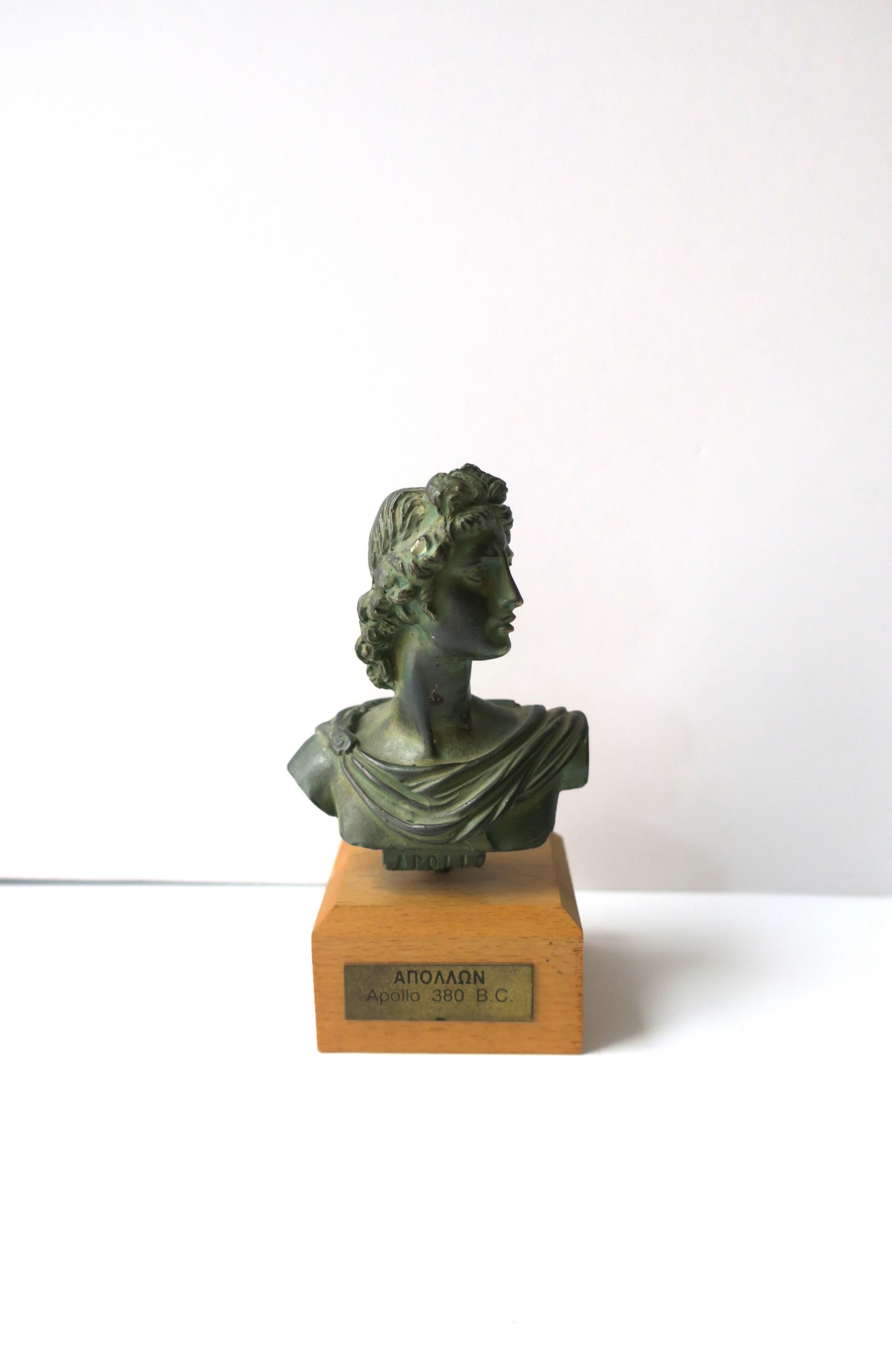 A small replica of the sculpture bust of Apollo in the Greco-Roman style, circa mid-20th century, Greece. A small replica of Apollo with a Verde green hue on a wood base. A great decorative object for a desk, shelf, table, home library, etc. With
