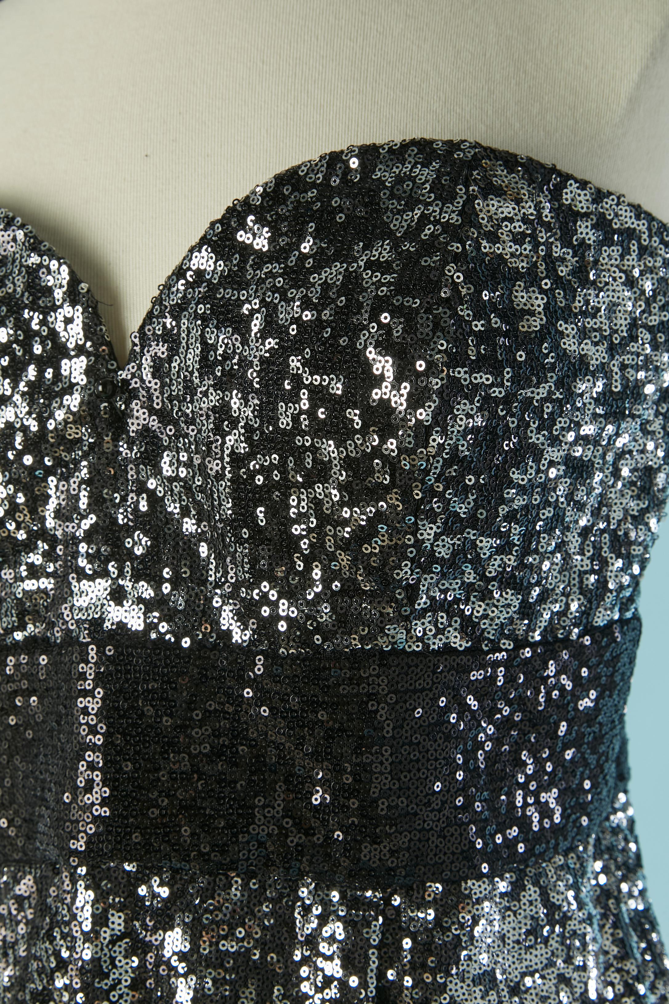 Abito da sera bustier in paillettes argento e nero. Principale  composizione del tessuto: 90% nylon, 10% spandex. Composizione della fodera: 100%  acetato. Chiusura con zip invisibile al centro della schiena + gancio e occhiello. Reggiseno sottile e