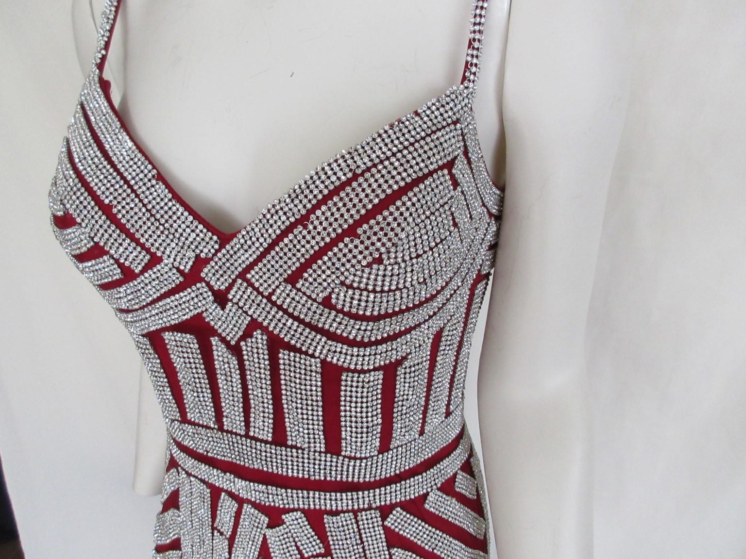 Vintage silver strass style bordeaux red evening dress. 

The exquisite shapely lines are heavily beaded in strass on red crepe material and is fully lined . 
The dress has a zip and hook-and-eye back closure. 
Bra cups are built into the lining.