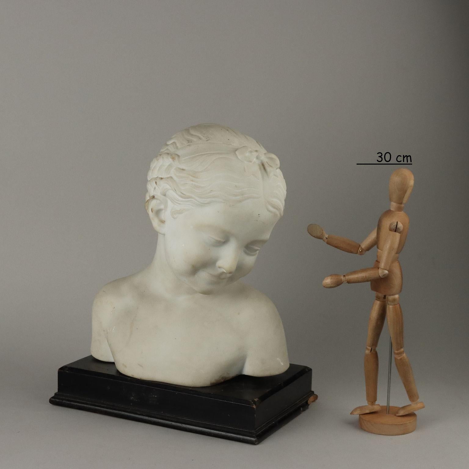 White marble sculpture depicting bust of maiden. Three-quarter face with downward gaze. Dark patina wood base.
