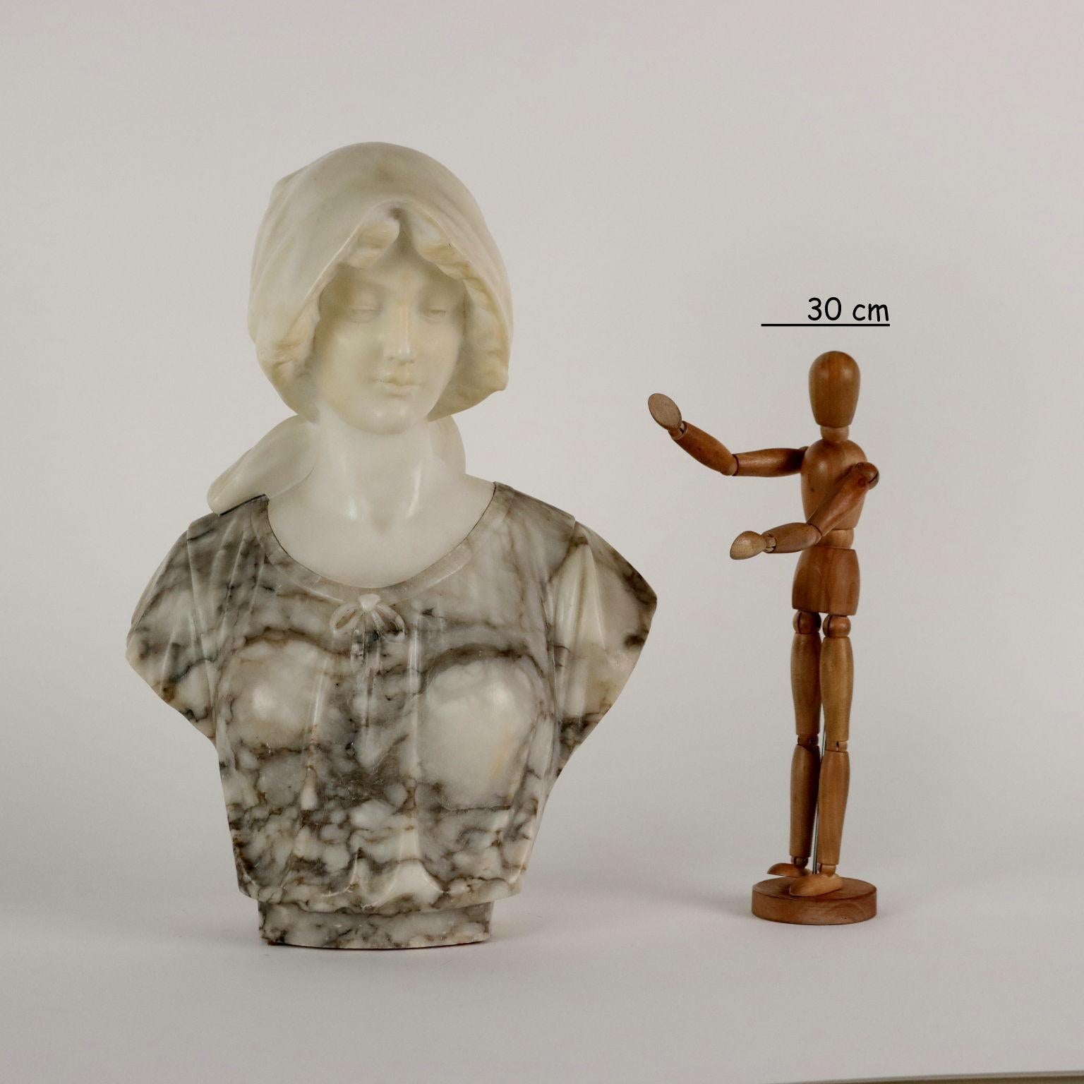 Bust of young woman in white marble and alabaster with veining in shades of gray.