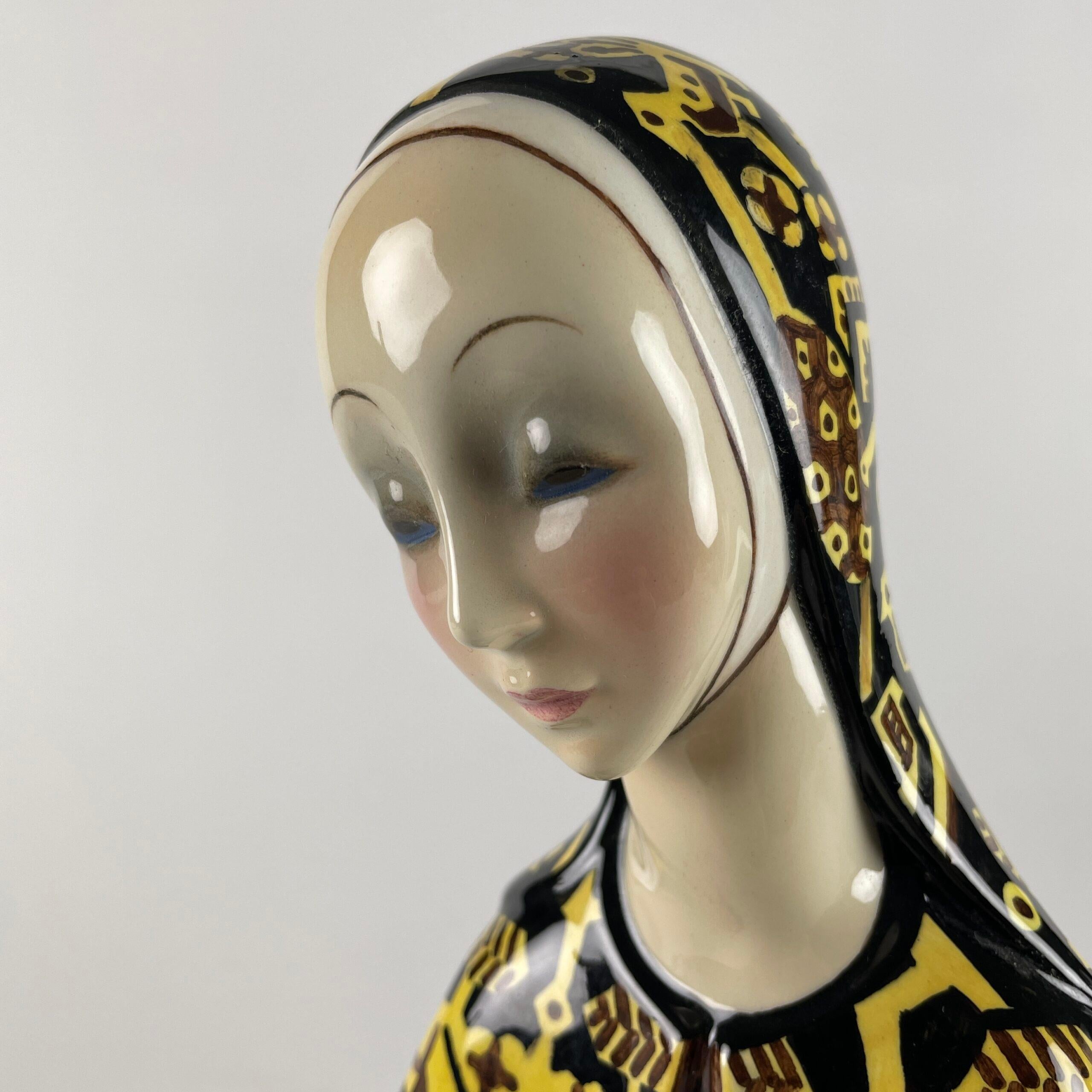 Figura Di Donna della manifattura italiana di ceramiche Lenci 1933 nota come Rassegnazione realizzata da Helen Konig Nero (1886-1974) raffigura una figura di donna con velo e mani incrociate in terraglia a colaggio con decoro a smalti policromi nei