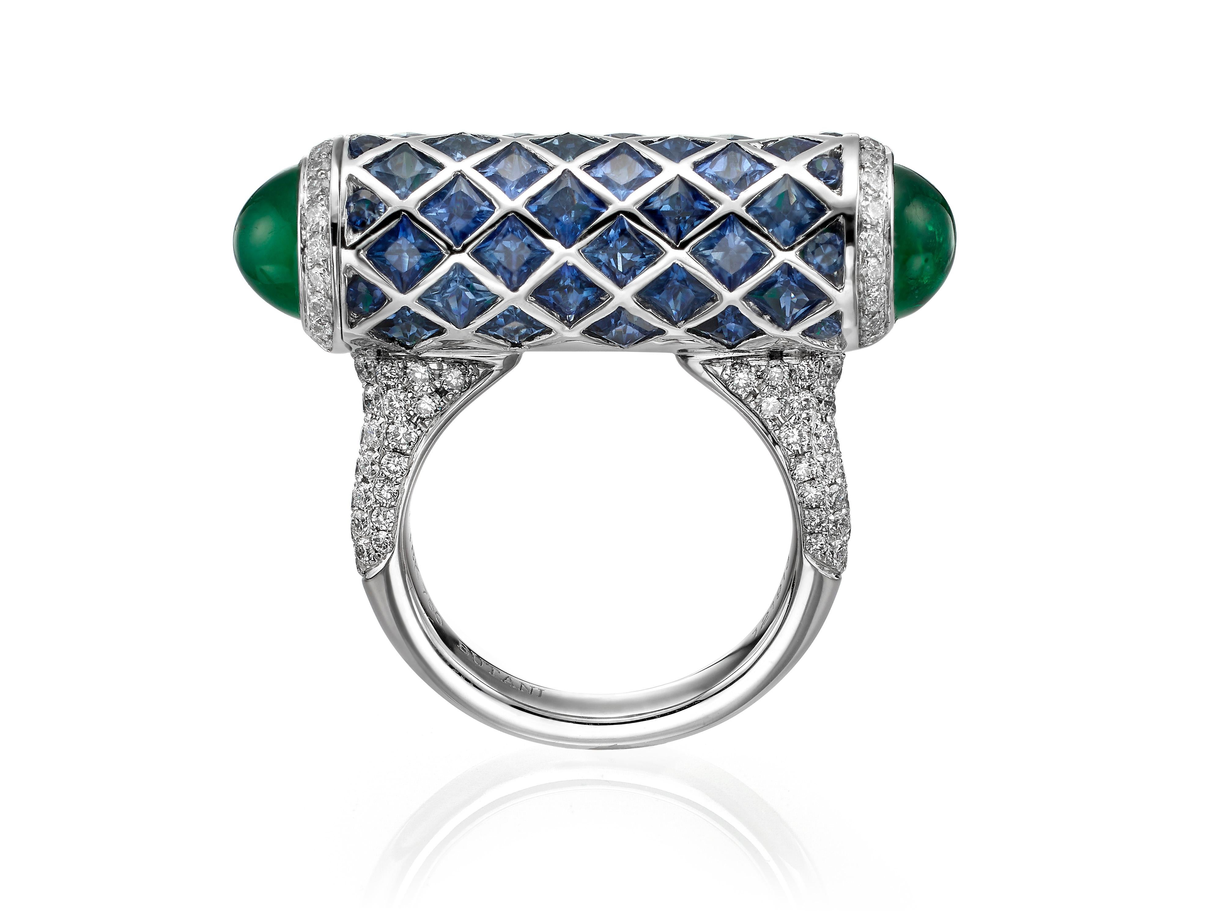 A one-of-a-kind secret compartment cocktail ring encrusted with 5.91 carats of royal blue sapphires and a brilliant lattice of 0.94 carats of white diamonds.  The ring is accented with two emerald cabochons (3.06 carats total) and hides a secret