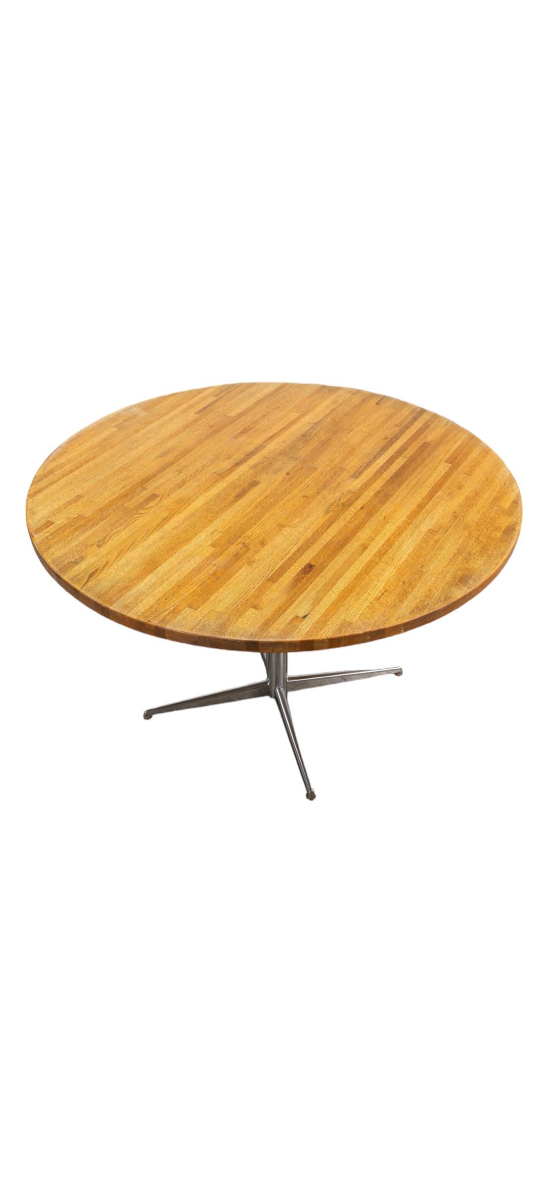 48” diameter round dining table. Elegant and efficient silhouette. Handsome as the main dining table in an apartment or perfect as a kitchen table in a home. In good condition with a tasteful refresh. Solid butcher block is sturdy atop cast metal