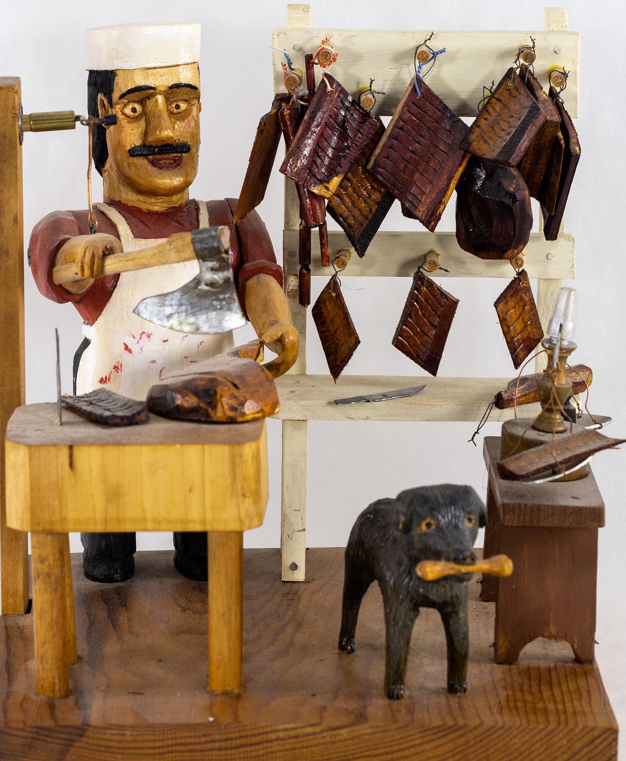 Carved and painted by John (Ivan) Bambic, b. 1922.
This mechanical animated sculpture features a butcher at his block
with meats hanging and a dog at his side.
Signed on the bottom.
 