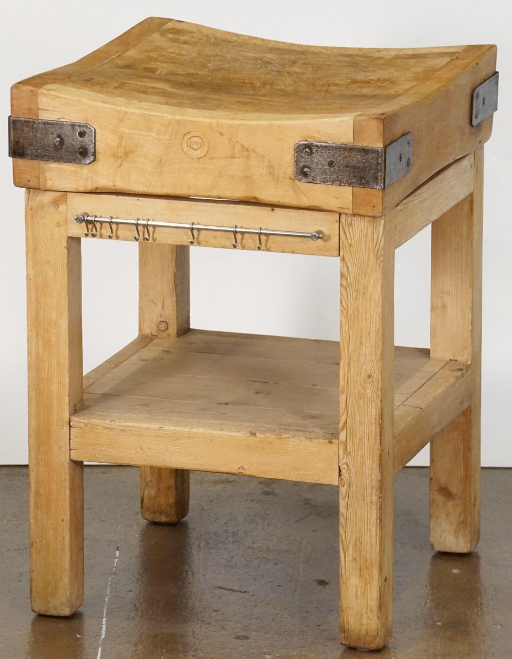 A handsome two-tiered butcher's chopping block on stand or table of pine and beech wood from England, featuring a large, square sloping block or slab of iron-bound wood set upon a sturdy bottom tier four-legged support stand of pine, with paneled
