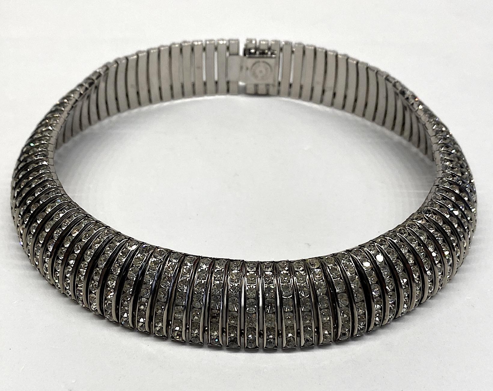 A truly chic rhinestone collar by English company Butler & Wilson from the 1980s. The design is a 1930s machine age Art Deco style. The necklace is comprised of rhodium plated 1 inches long links. Each link is channel set with 7 round rhinestones