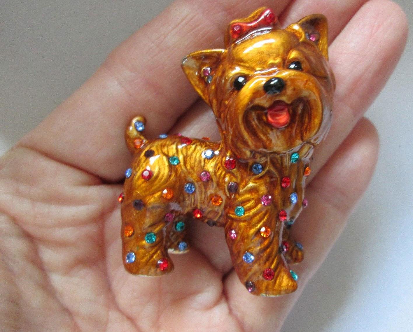 Adorable Terrier Dog Glossy brown Enamel encrusted with sparkling seed crystal glass in tones of turquoise, ruby, citrine & amethyst with a pink enamel tongue, jet nose and eyes dressed up in a pink bow. Roll over clasp; Signed to the reverse:
