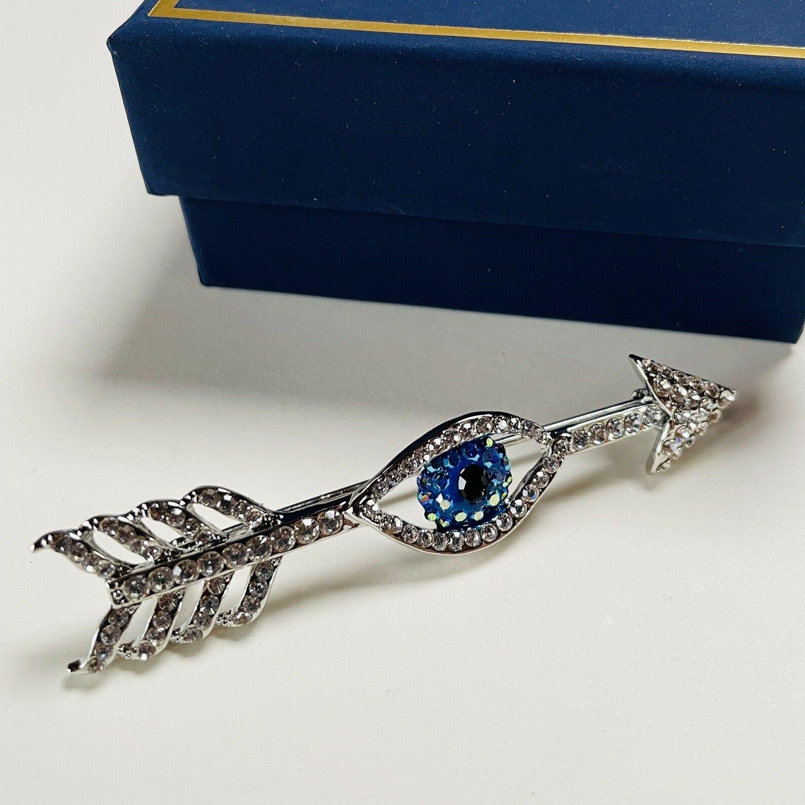 Awesome Signed Butler & Wilson Eye and Arrow Brooch. Hand set with Sparkling blue and clear Crystals. Silver plated mounting. Measuring approx. 3” long. Original Box. A piece you’ll turn to time and again…The perfect accessory for the Modern Woman! 
