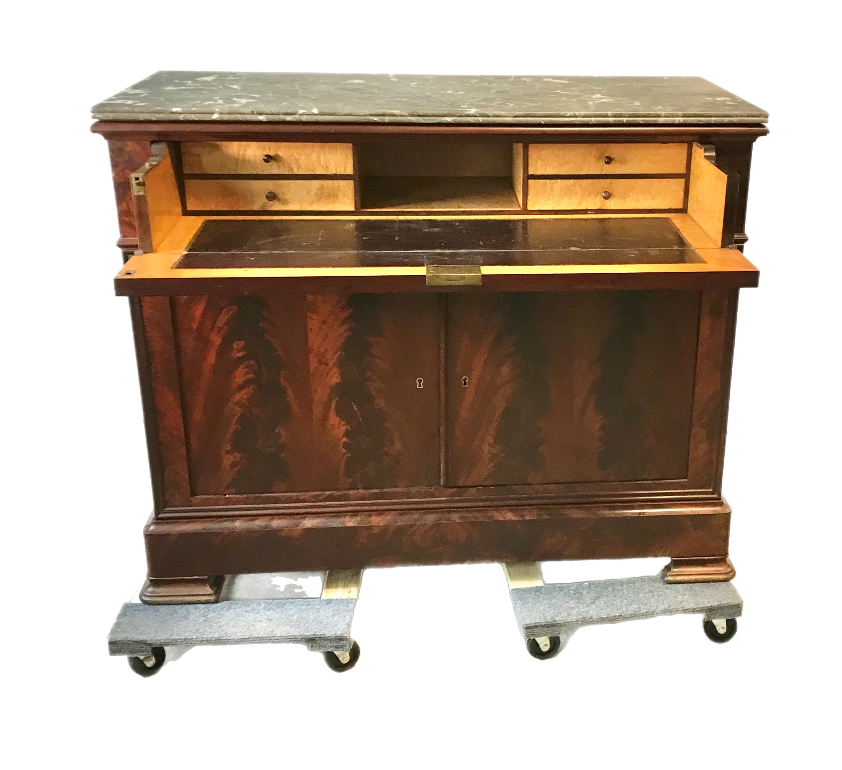 This Butlers desk features a flame mahogany veneer exterior with solid marble top. The interior opens to a desk with a stunning birdseye maple veneer finish and leather inlay writing surface. The lower compartment features 3 linen drawers with