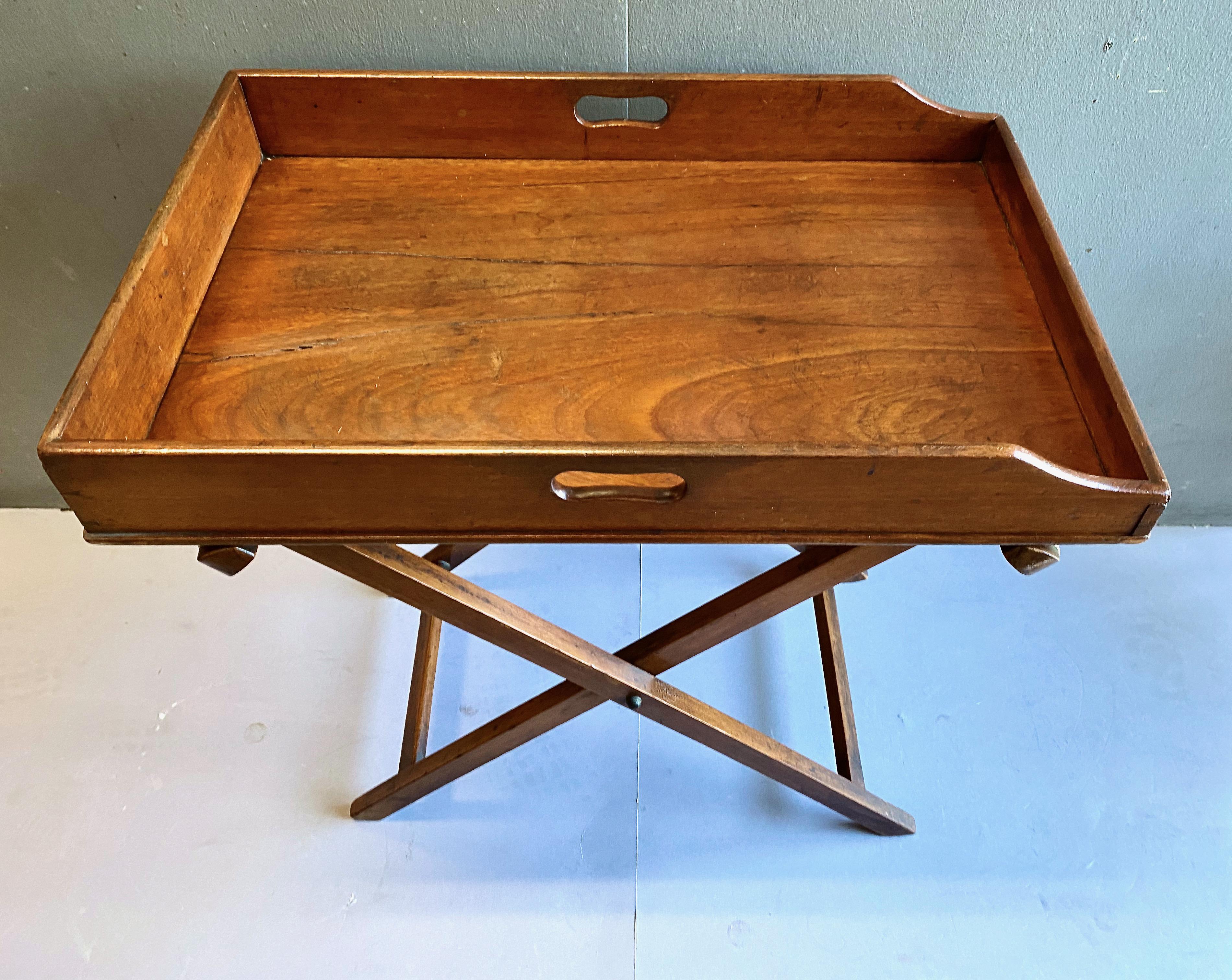 This is a classic early 19th century Mahogany Butler's Tray-On-Stand. The single board mahogany tray is framed by a 3 inch mahogany gallery on three side and a lower galley on the fourth side. The tray is in overall good condition with indications