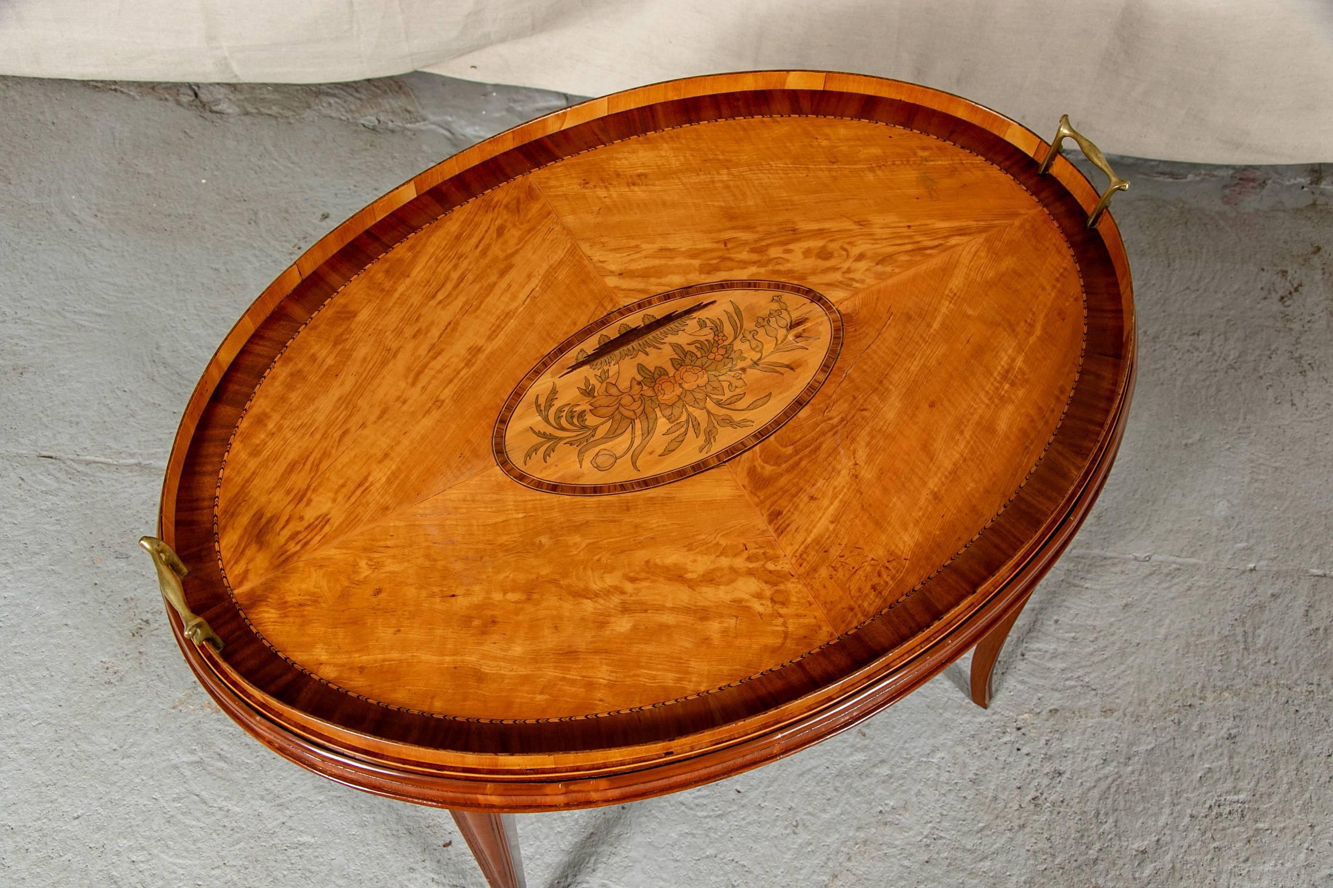 Butler's tray table, oblong top with flanking brass handles and central floral cartouche, supported on base with tapering splayed legs.

Condition: Very good with minor age/use wear including some very light scratching.