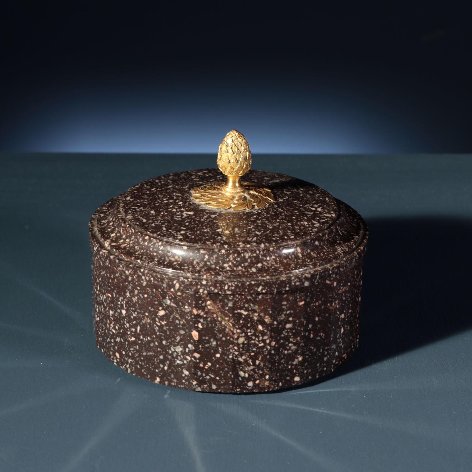 Casket in Swedish porphyry, the faceted cylindrical body is equipped with a slightly rounded circular lid with spiral facets, with a pinecone-shaped gilded bronze grip and connected to the porphyry with a crown of laurel leaves.