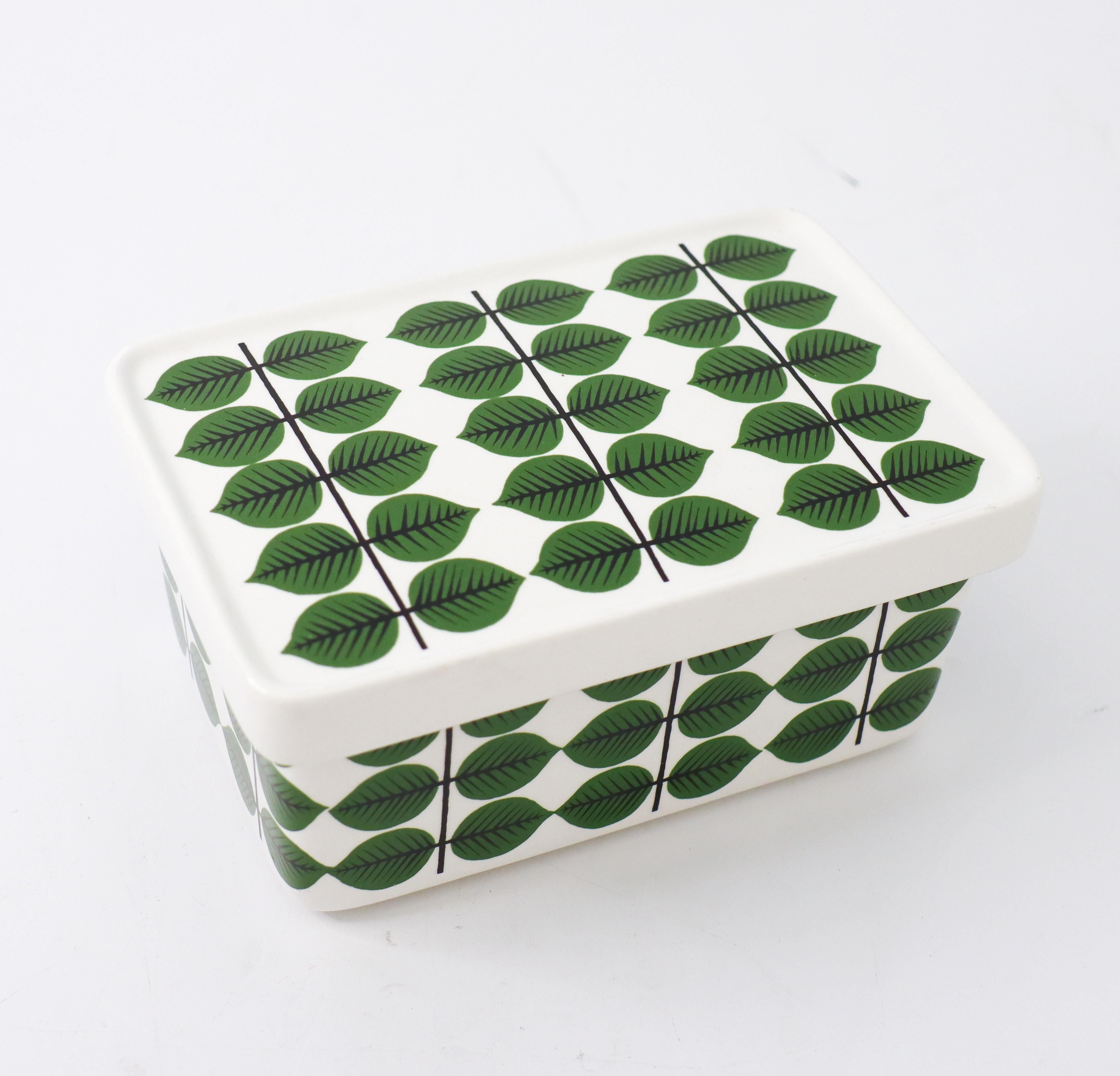 A lidded box in porcelain in the very famous pattern Berså designed by Stig Lindberg at Gustavsberg. This was original made as a butter dish but can be used as a box as well. It is 16.5 x 11 cm in diameter and 6 cm high. It is in mint